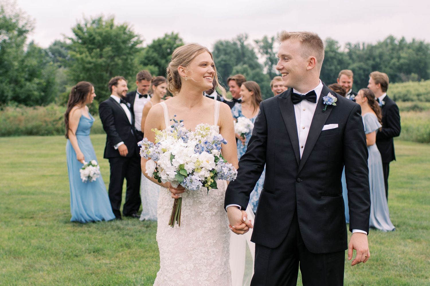 Newlywed couple walking together holding white floral bouquets on their wedding day.