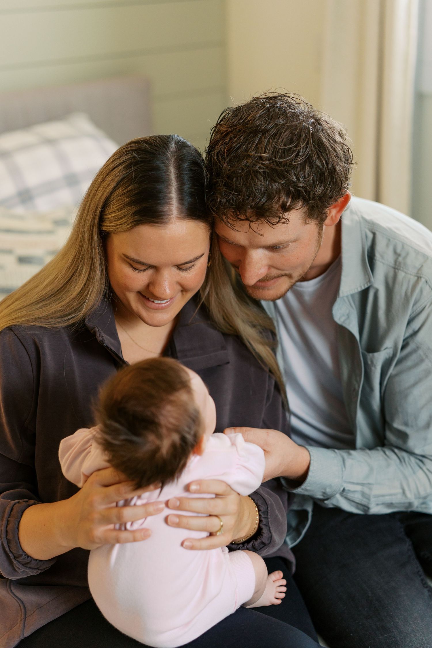 Loving moments shared with a baby in pink clothing on a couch.