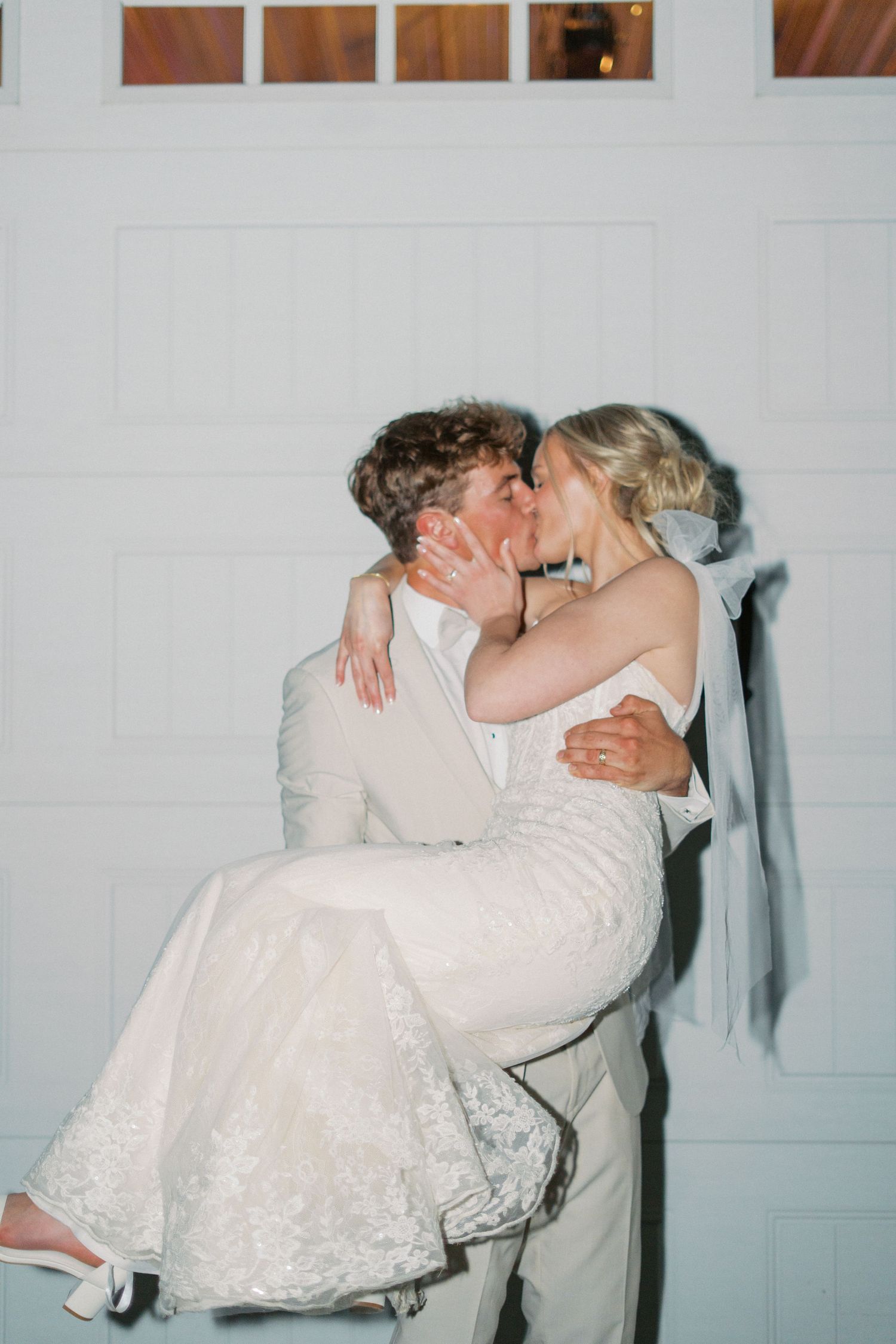 A romantic dance dip sequence between a couple in formal wedding attire against a white wall.