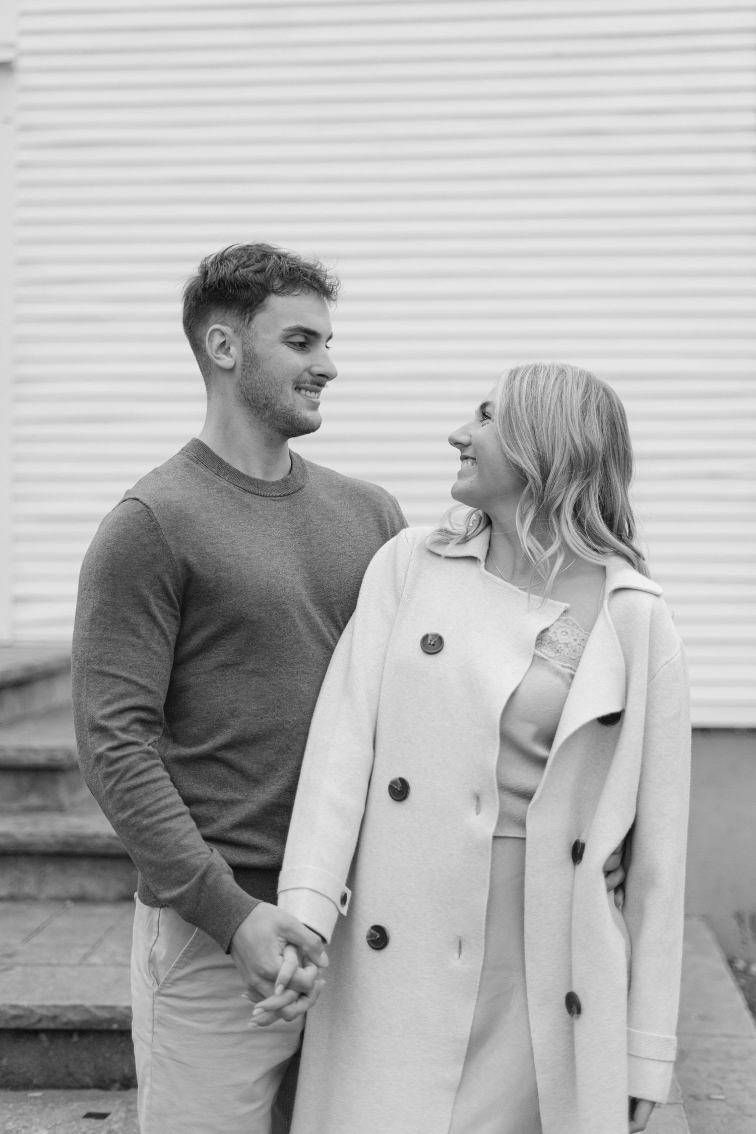 Black and white photo of a couple laughing together wearing winter coats.
