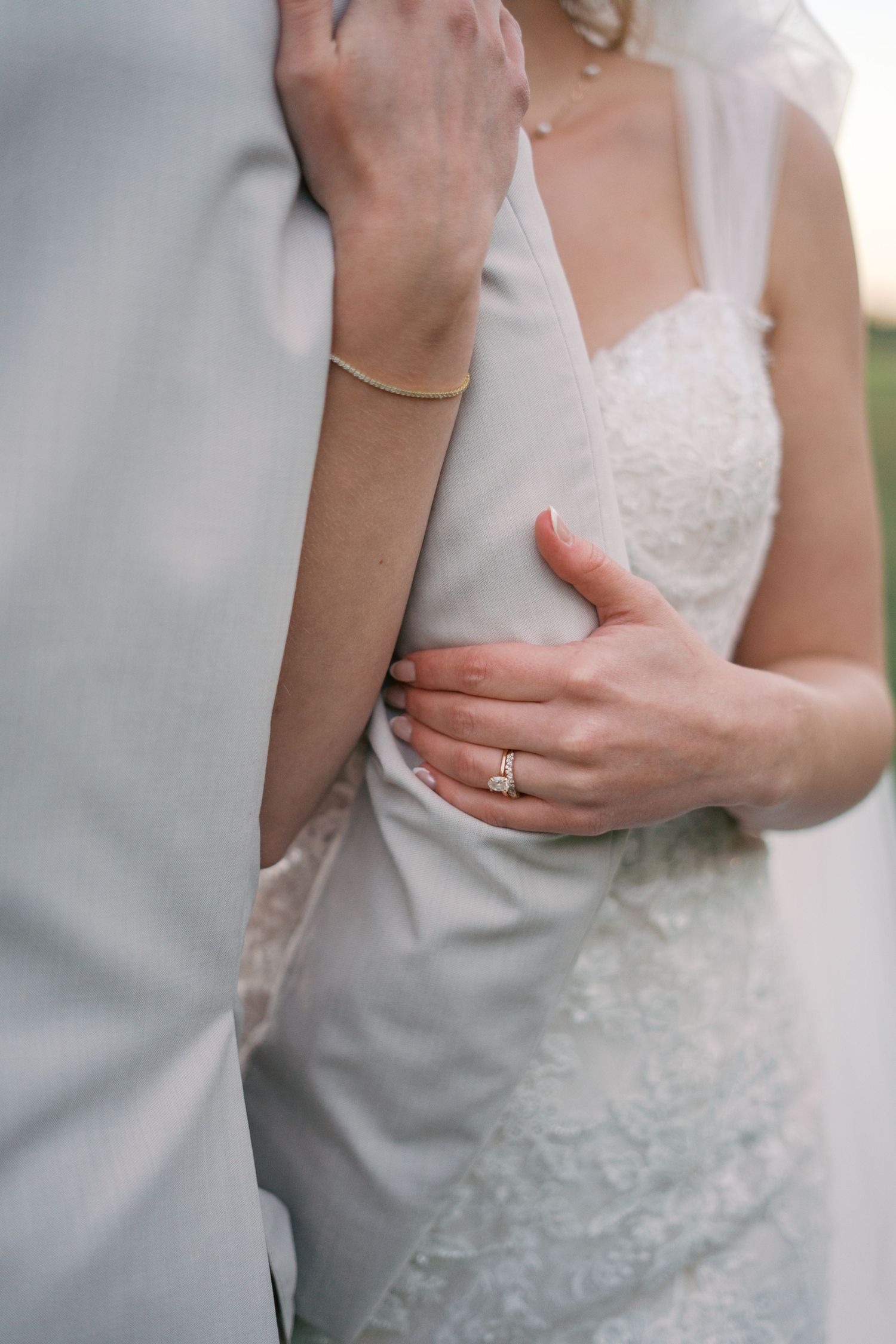 Close-up details of a white lace wedding dress and engagement ring.