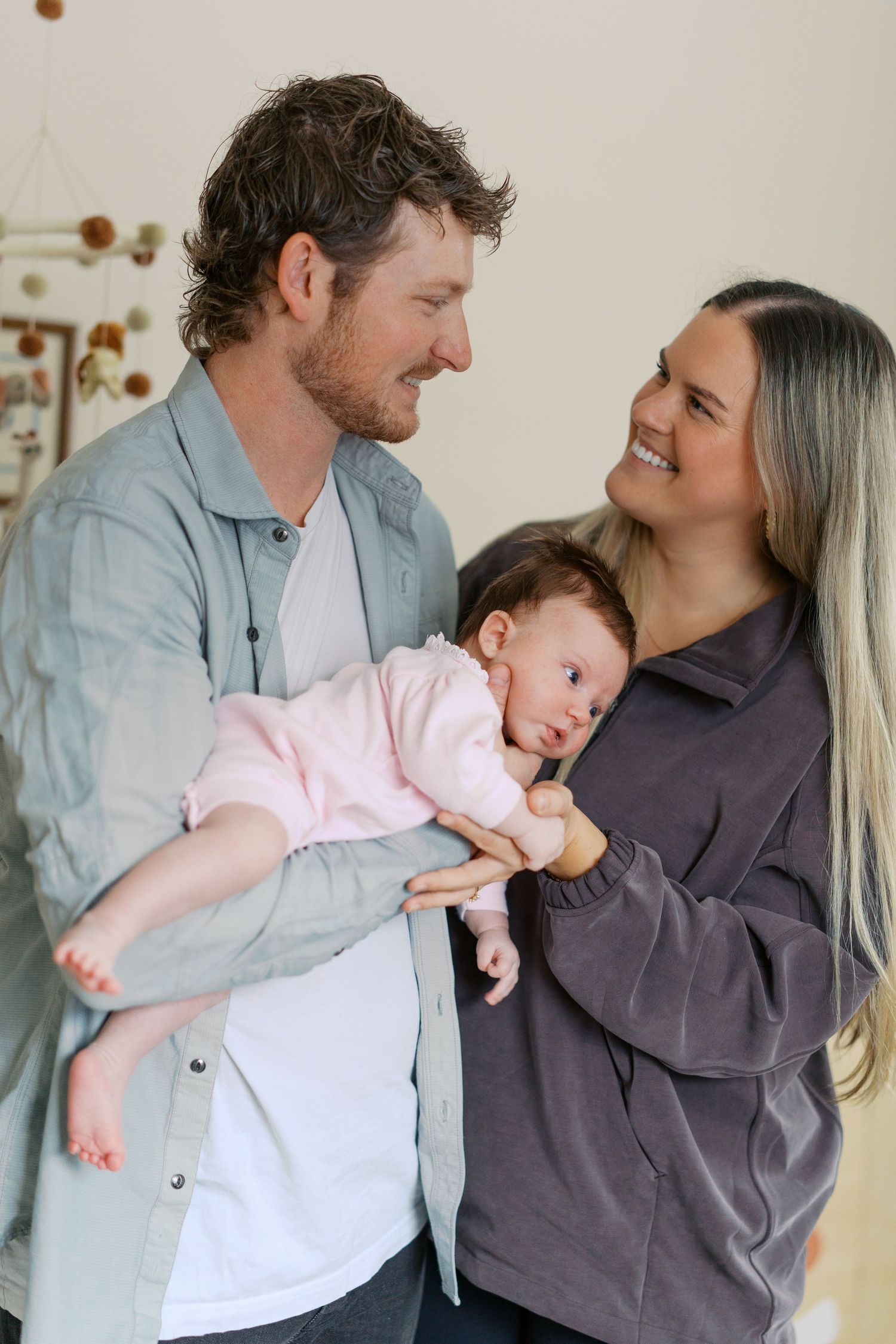A couple sharing joyful moments with their newborn baby in a bright room.