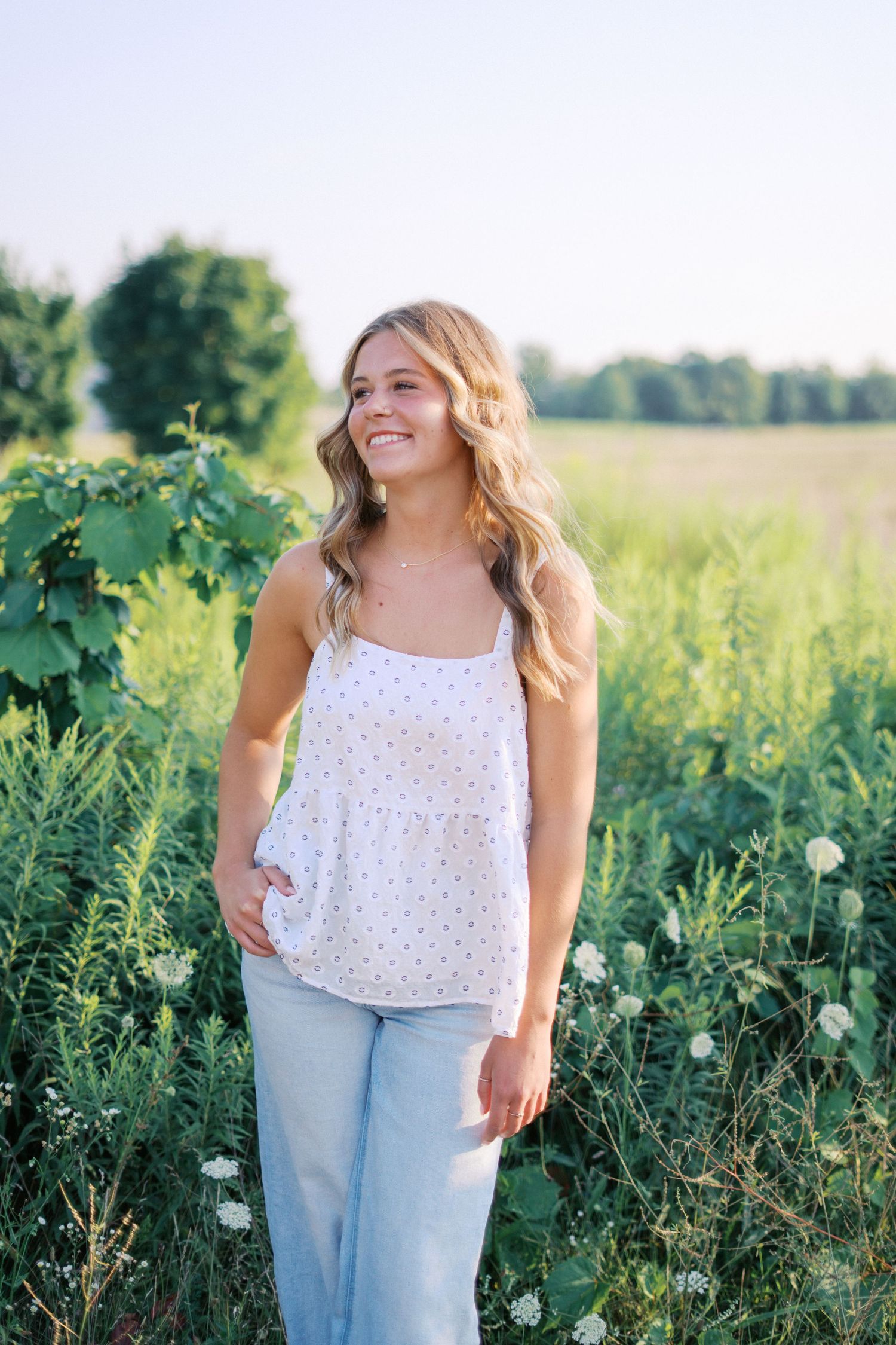 A casual outdoor portrait session among blooming wildflowers and greenery on a bright summer day.