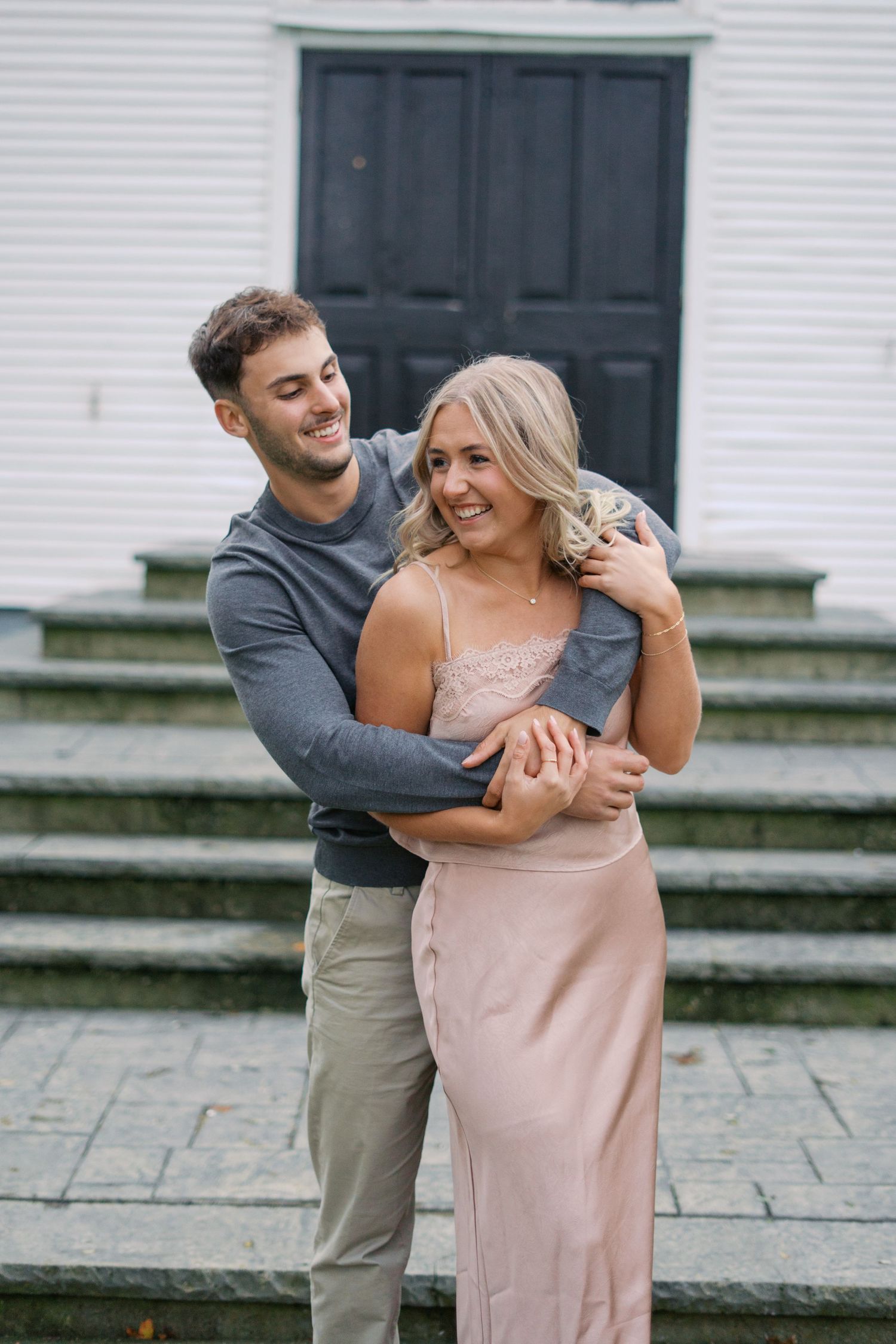 Dancing couple in coordinated outfits share a romantic moment outside a church.