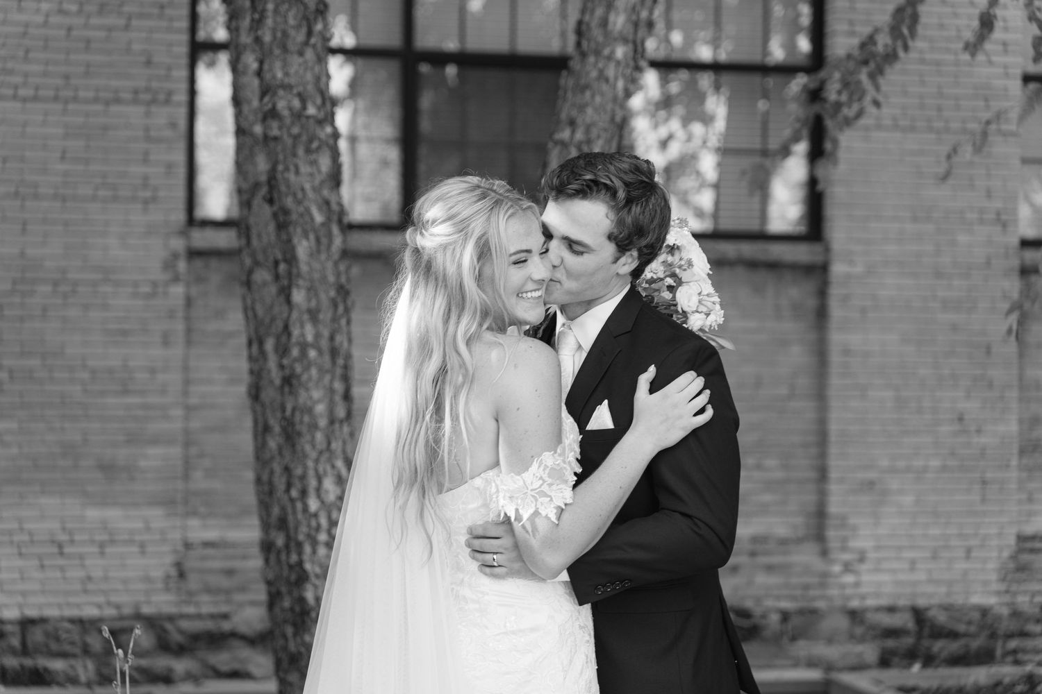 Black and white portrait of couple sharing intimate moment during wedding photoshoot.