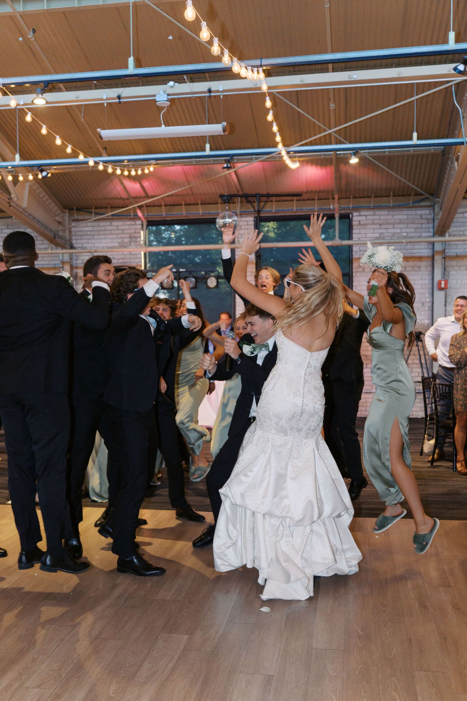Wedding party members perform synchronized dance moves at a reception.