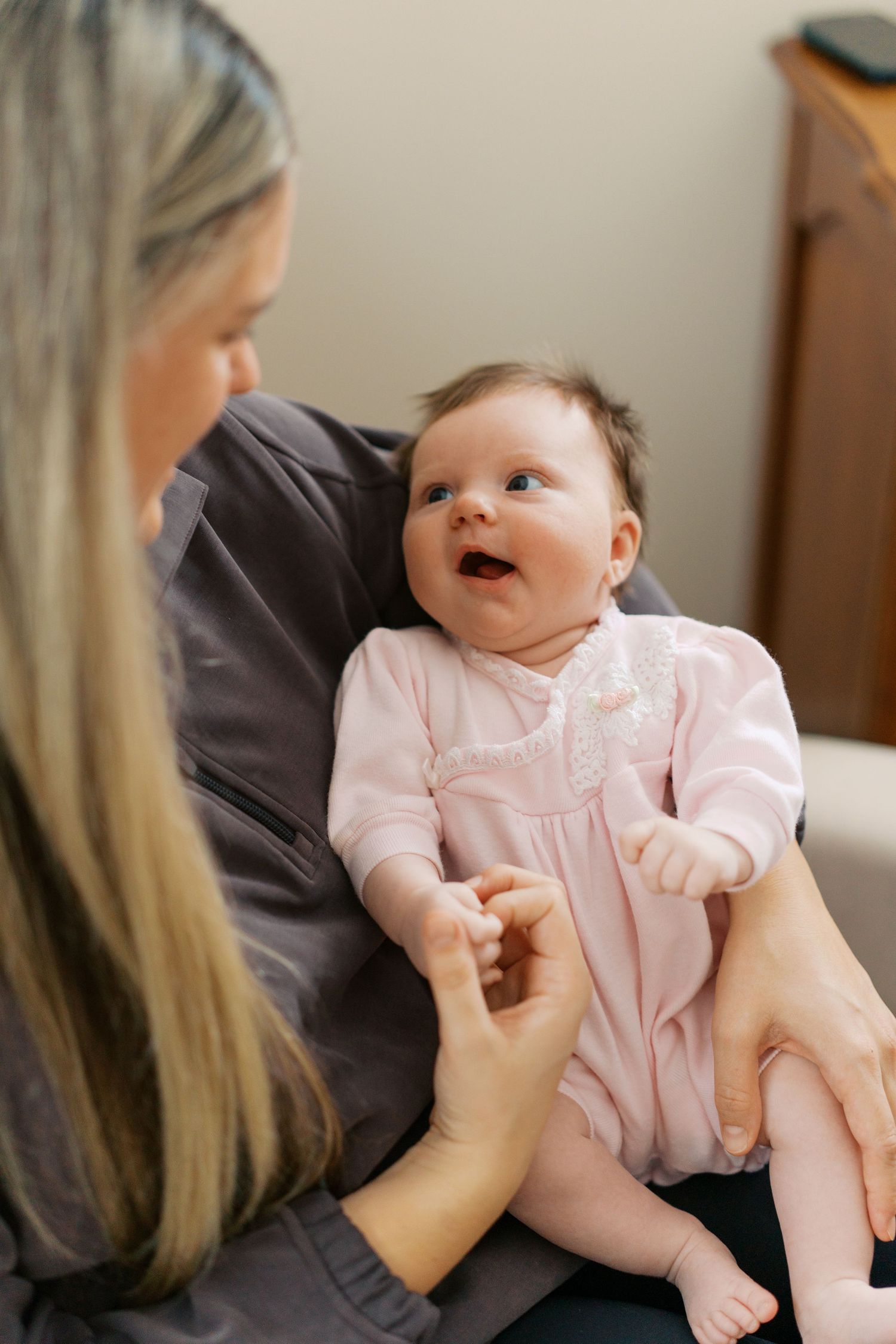 Baby in pink outfit sharing playful moment with parent.