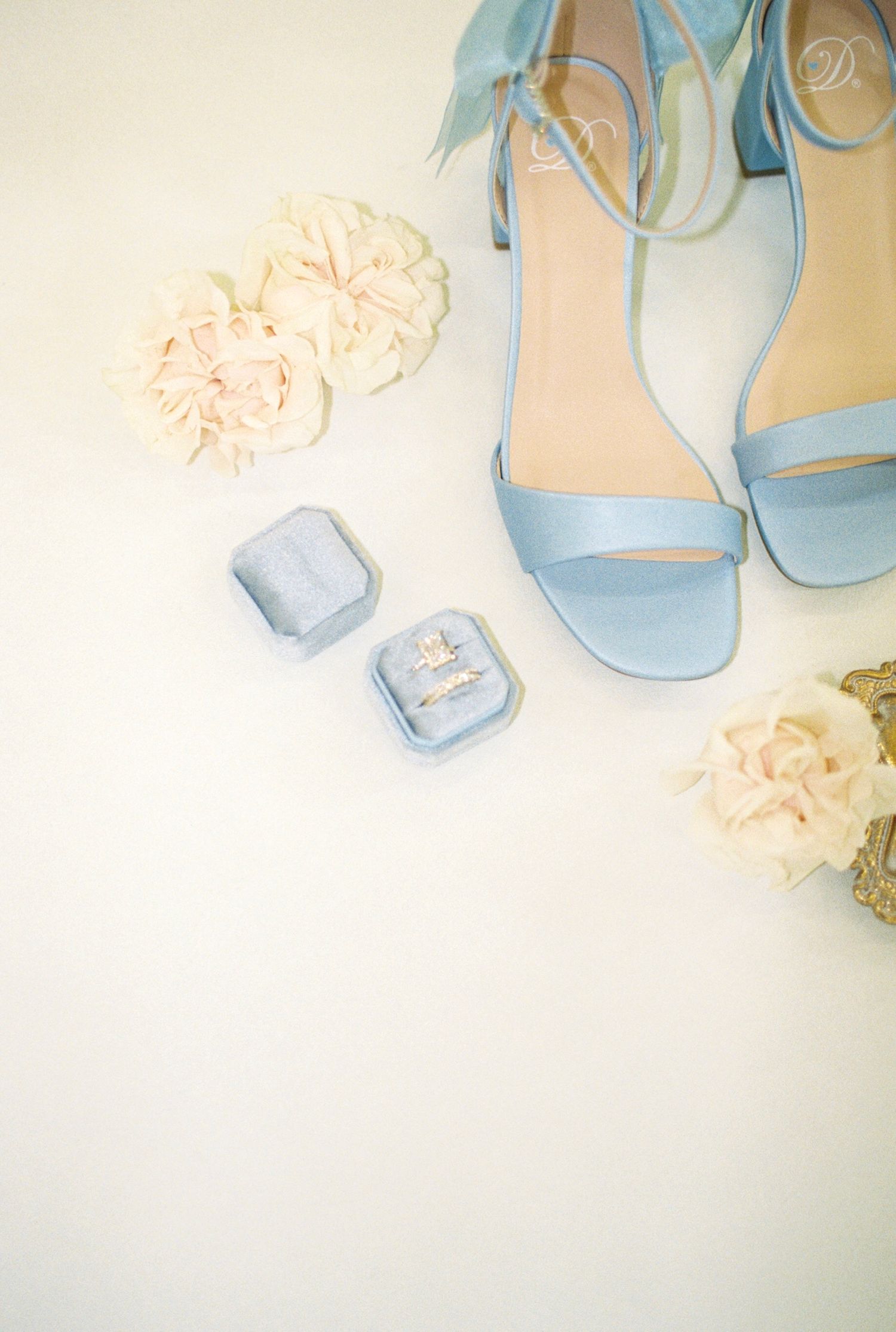 Light blue wedding shoes with delicate floral details on white background.