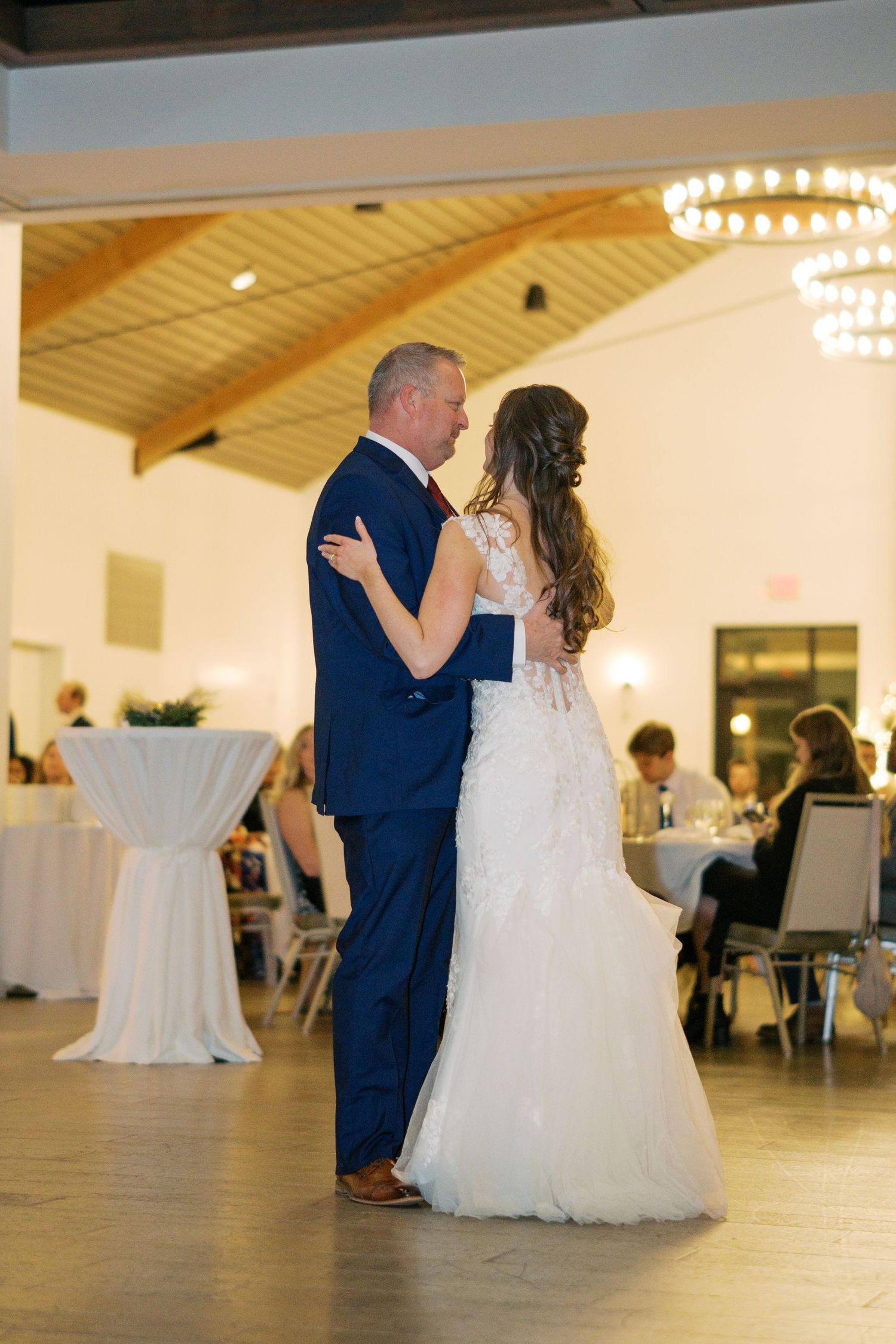 Couples dancing under elegant chandeliers in a modern wedding reception venue.