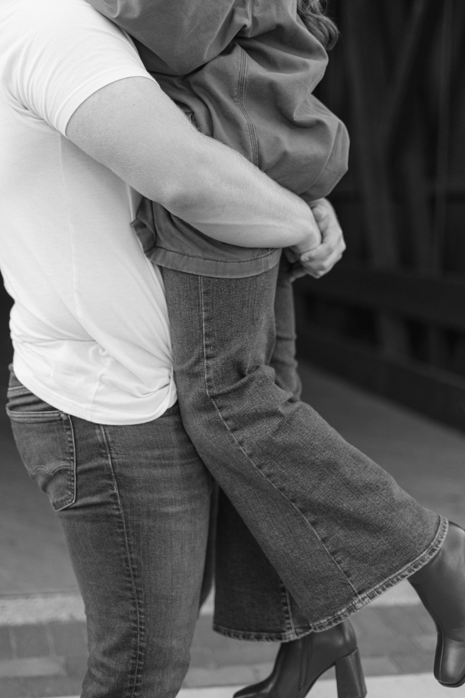 Playful couple in casual wear dancing together in black and white.