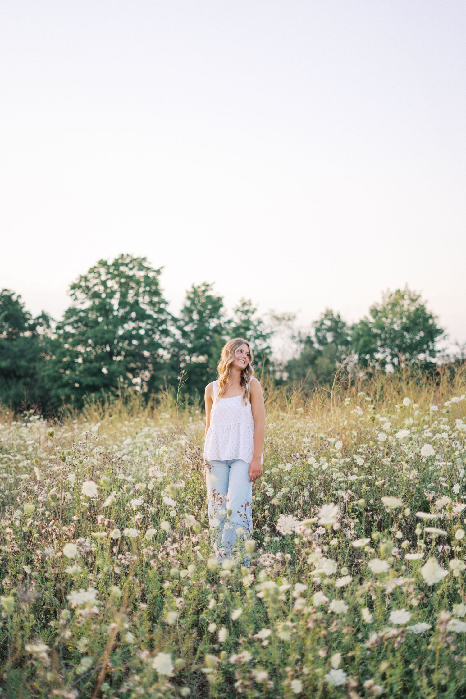 Serene outdoor portrait in a meadow filled with white wildflowers during golden hour.