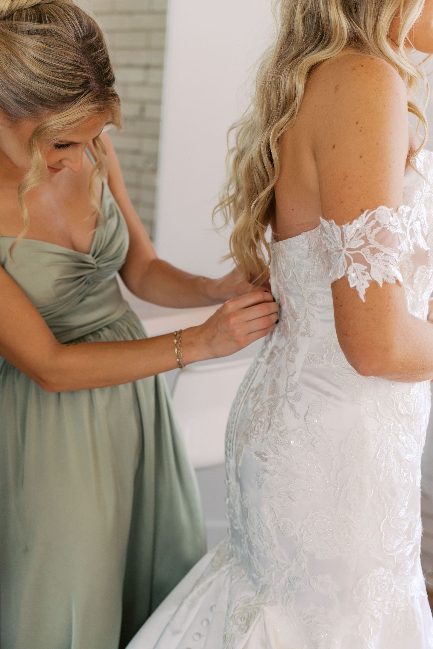 Detail shots of a white lace wedding dress with sage green bridesmaid dresses.
