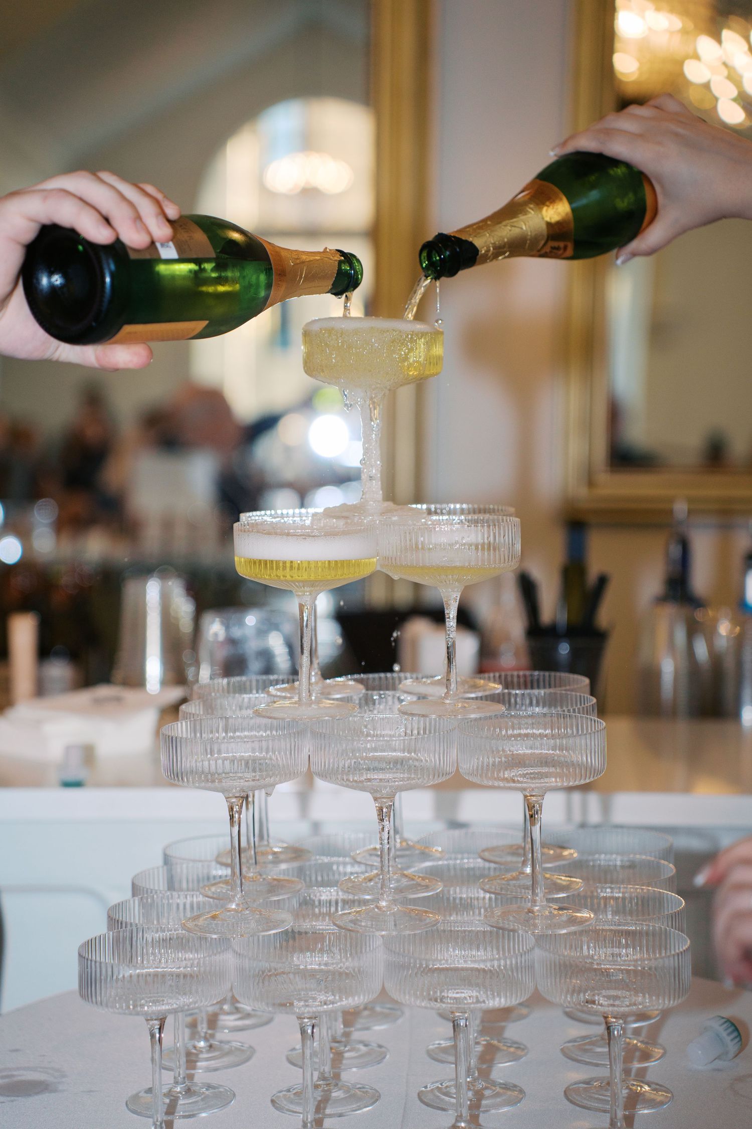 Champagne being poured into a tower of stacked crystal glasses at an event.