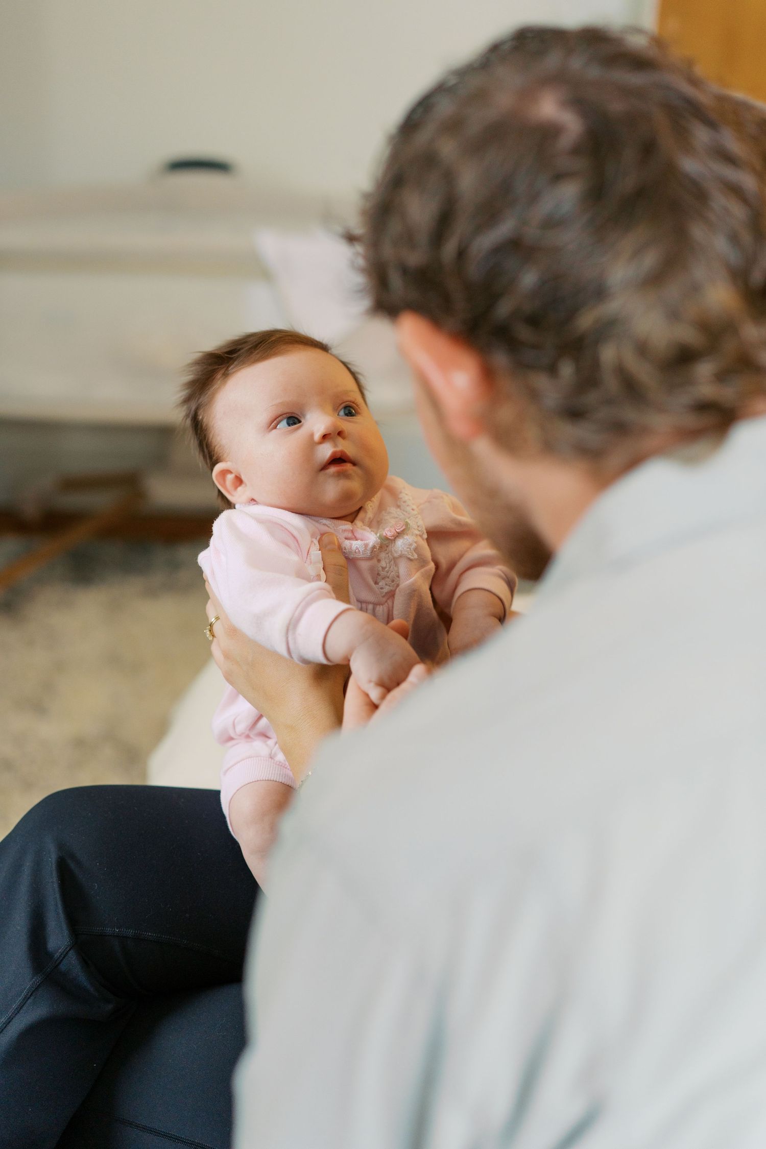 Sweet tender moment between parent and baby in pink outfit.