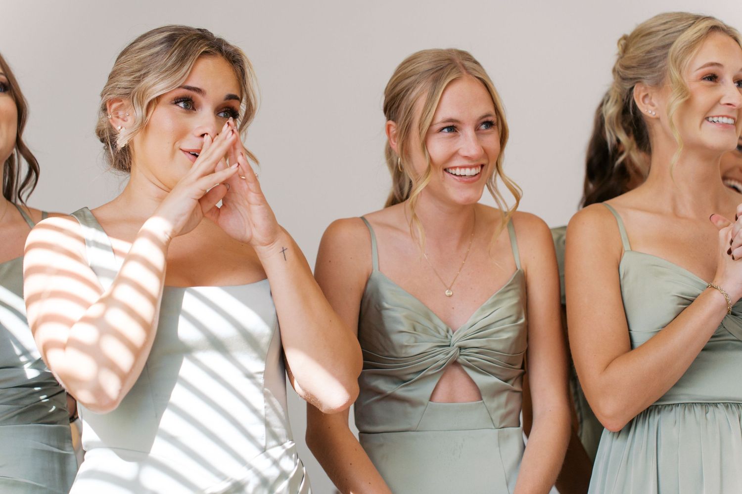 Bridesmaids in sage green dresses sharing joyful moments.