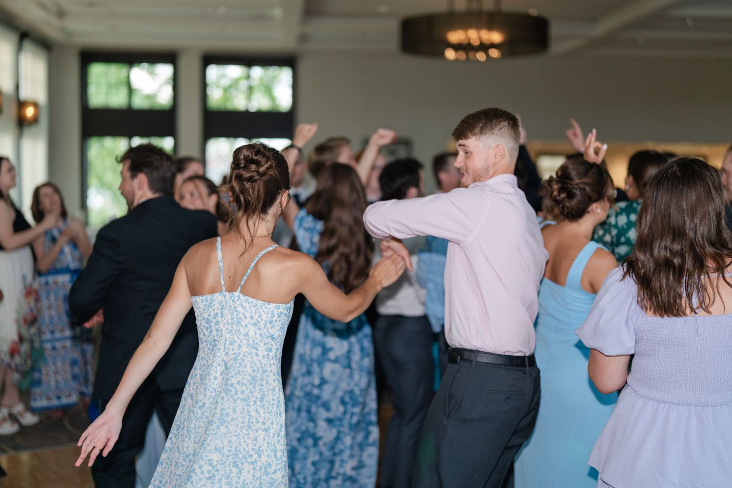 Wedding guests enjoying themselves on the dance floor in blue and pastel dresses.