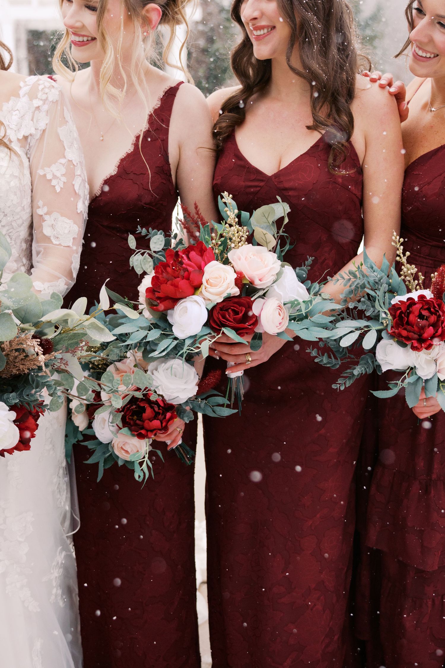 Close-up of wedding bouquets with red roses, white flowers, and eucalyptus leaves.
