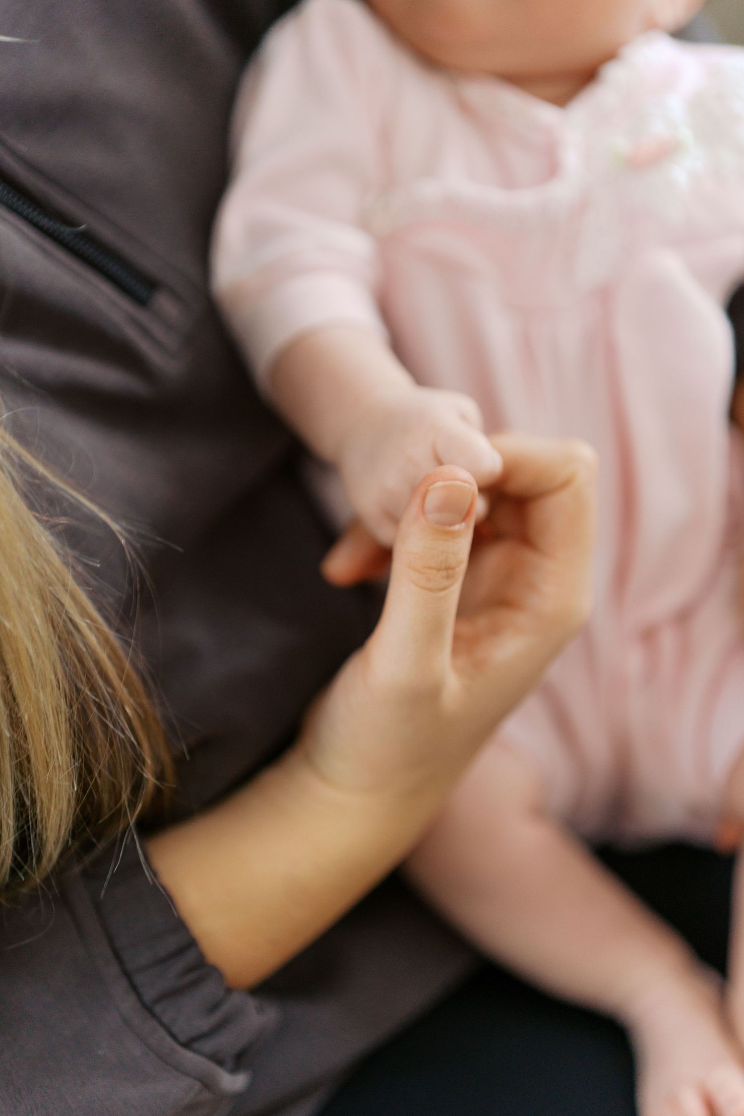 Close-up of baby's hand being held during intimate moment.