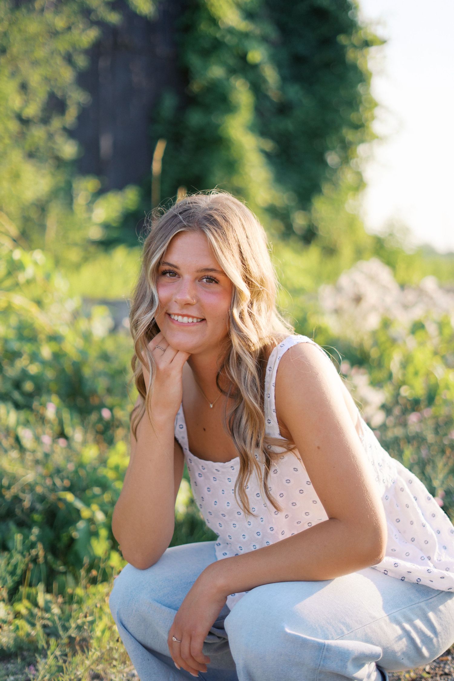 Natural light portrait captured in a lush garden setting with vibrant green foliage.