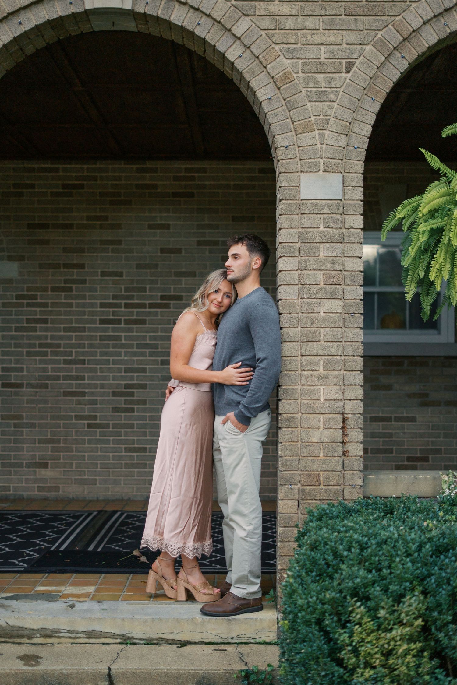 A romantic moment shared between two people under brick archways with greenery.