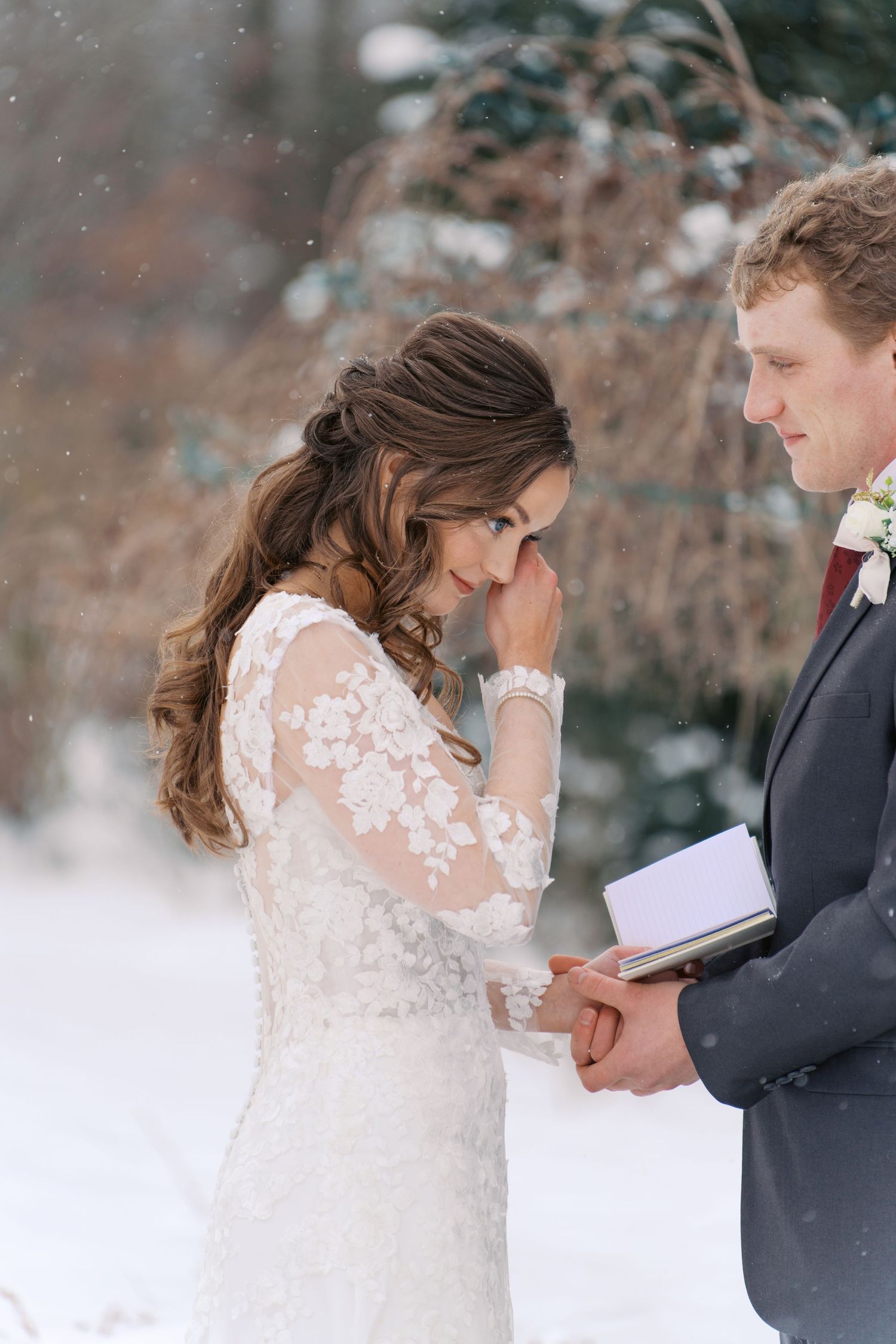 Intimate winter wedding moment captured with snowflakes falling in the background.