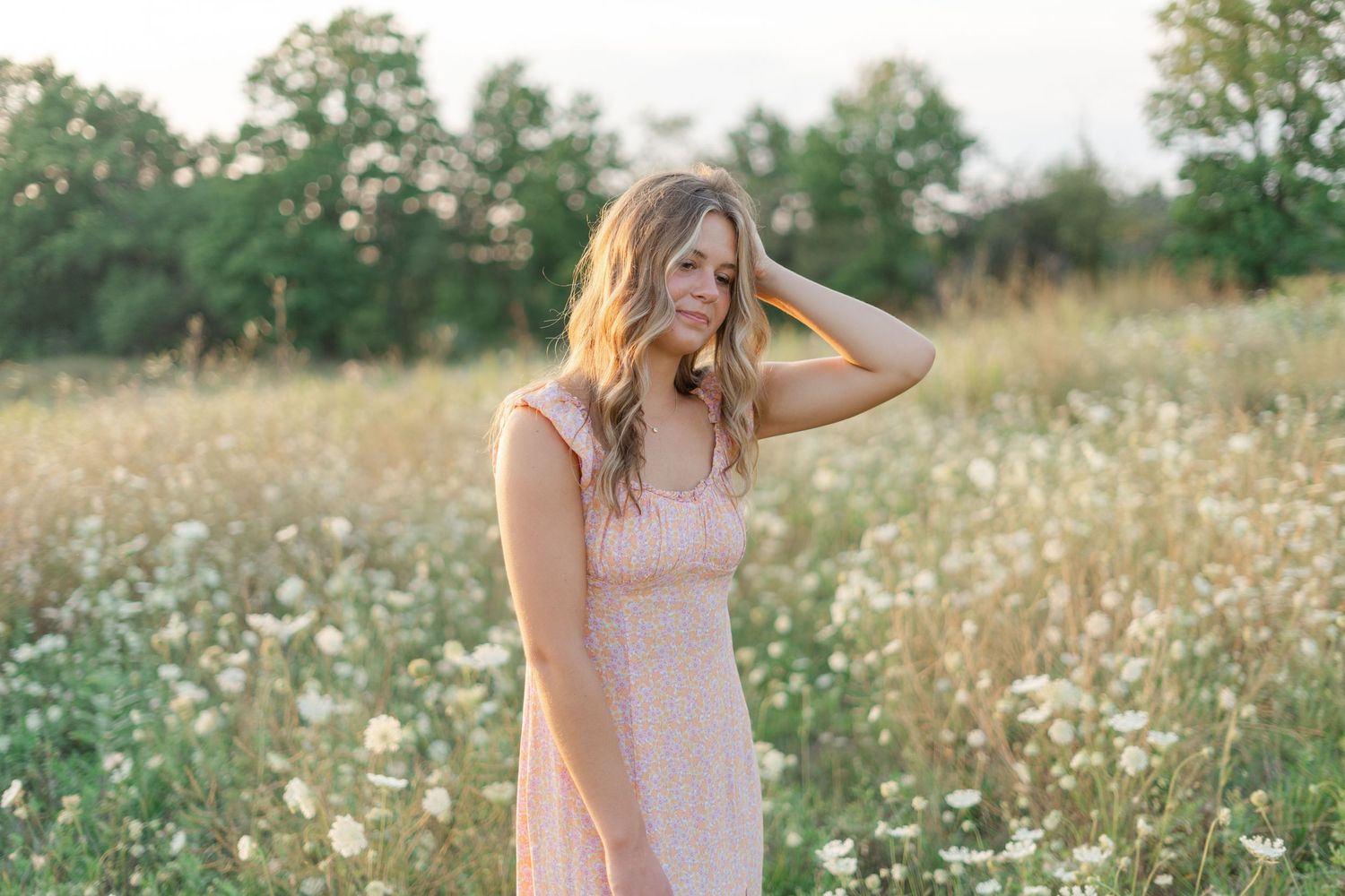 Ethereal summer portrait in a field of white wildflowers during golden hour.