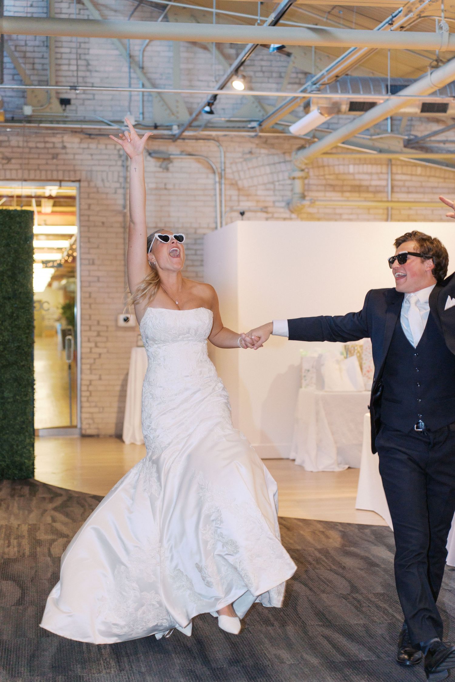 A couple dances playfully in an industrial-style venue with exposed brick walls.