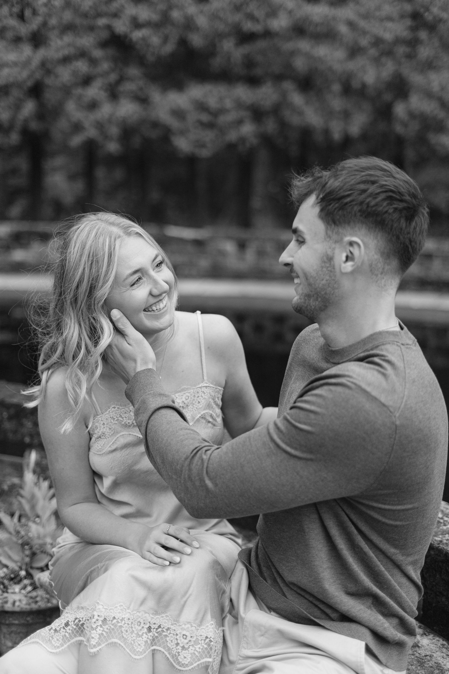 A tender moment captured in black and white of a couple sharing laughter outdoors.