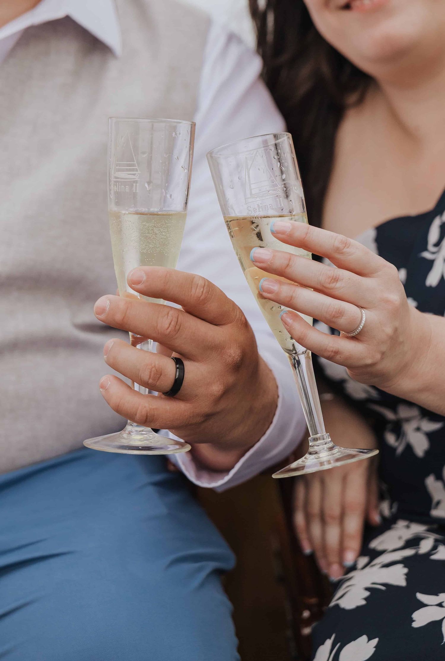 Close-up of hands holding champagne glasses during a celebration, with a wedding ring visible on one hand.