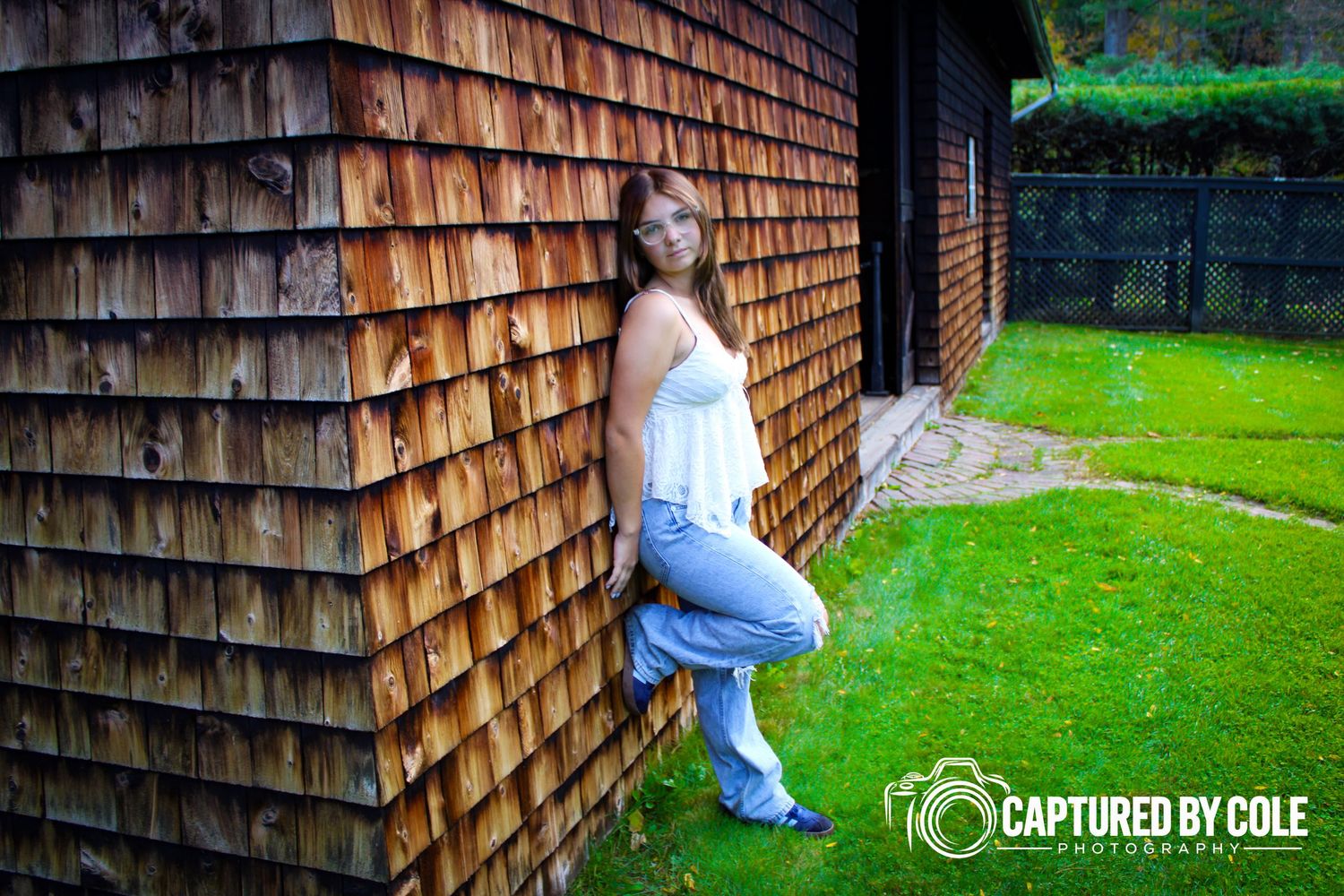 This is a picture of a girl leaning against a barn