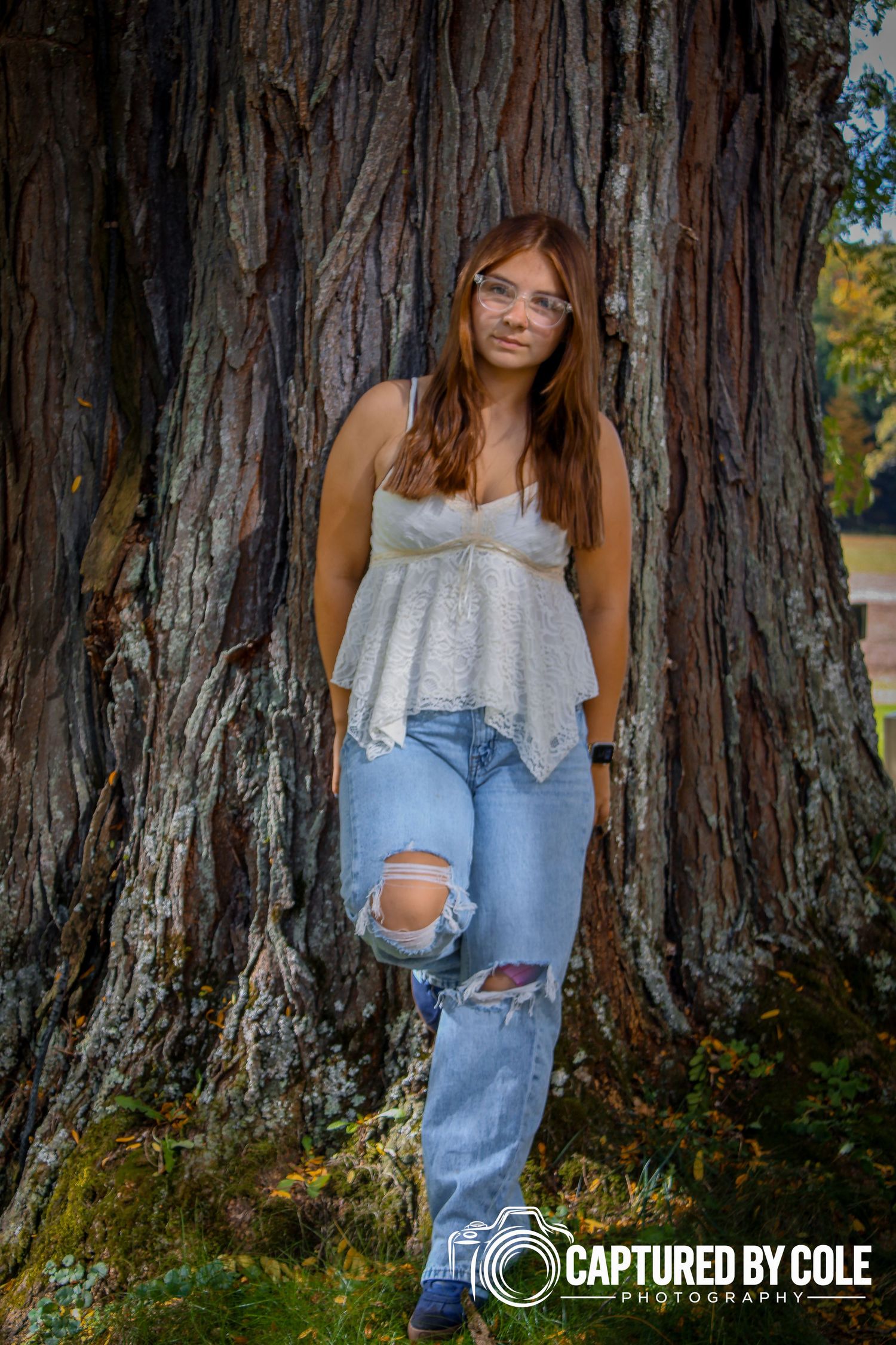 This is a picture of a girl leaning against a tree