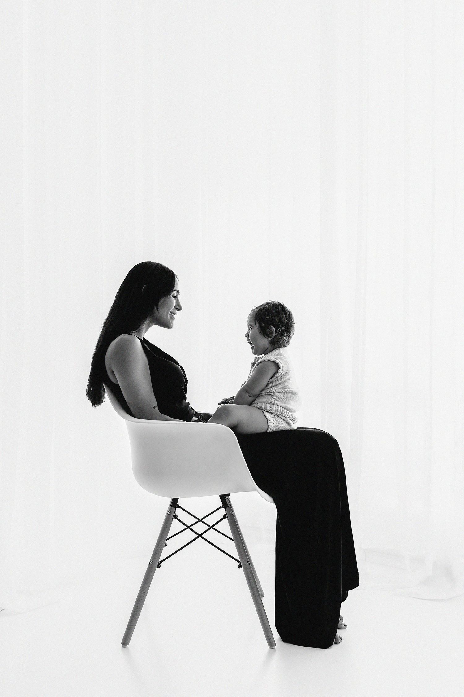 Minimalist black and white portrait of parent and child on modern chair.