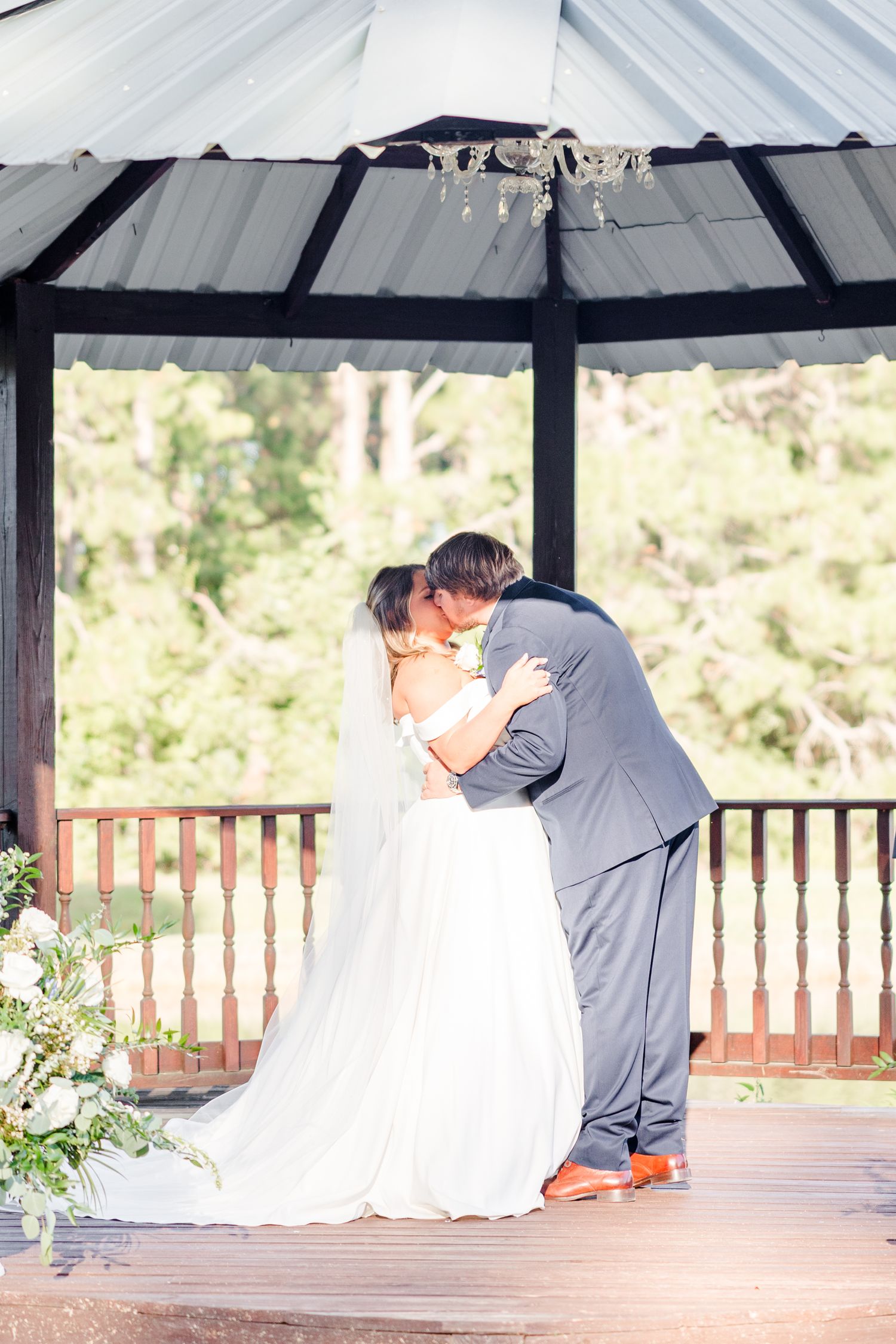 Intimate wedding moment captured under a covered pavilion with wooden railings.