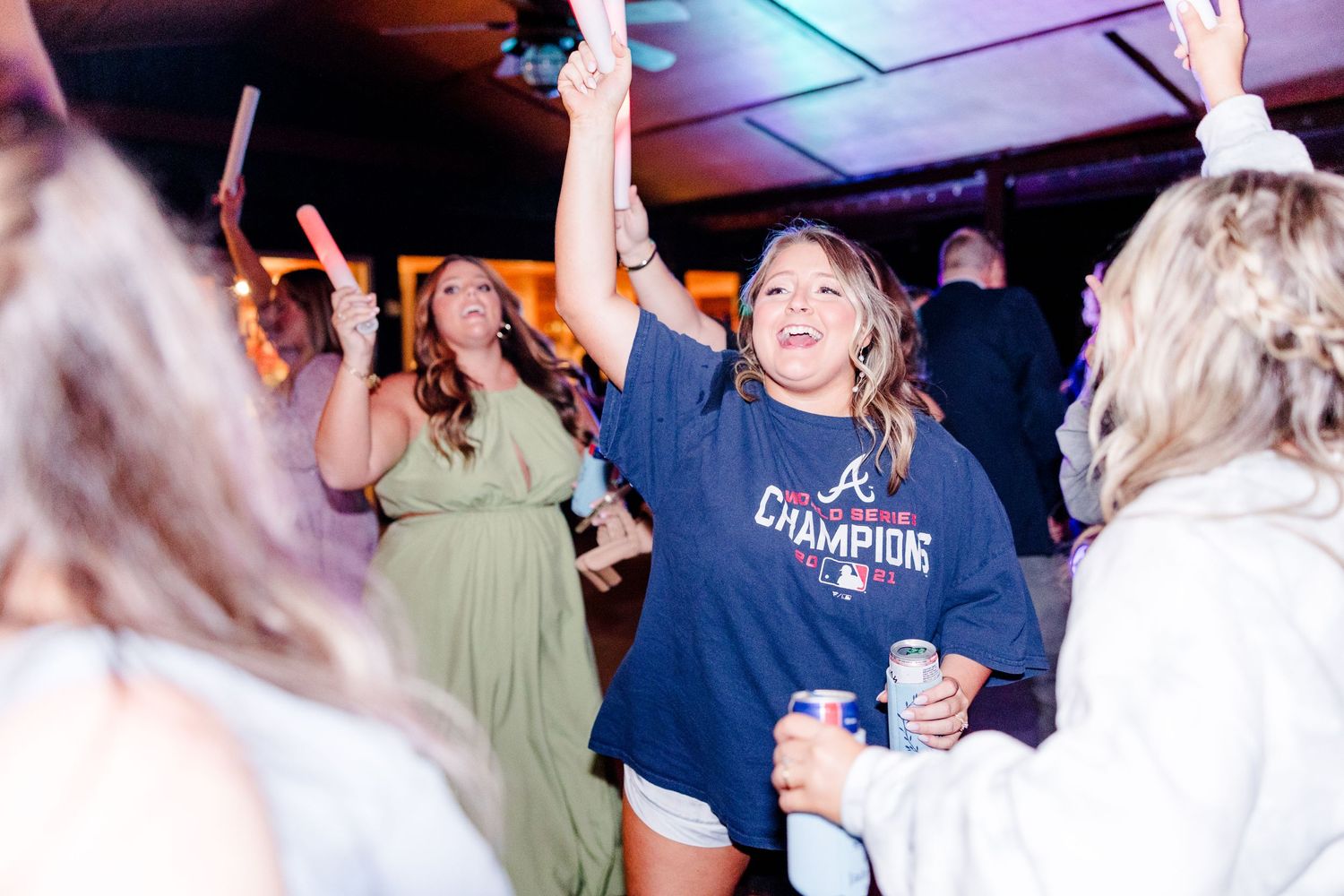 Wedding reception guests dance and celebrate under evening lighting.