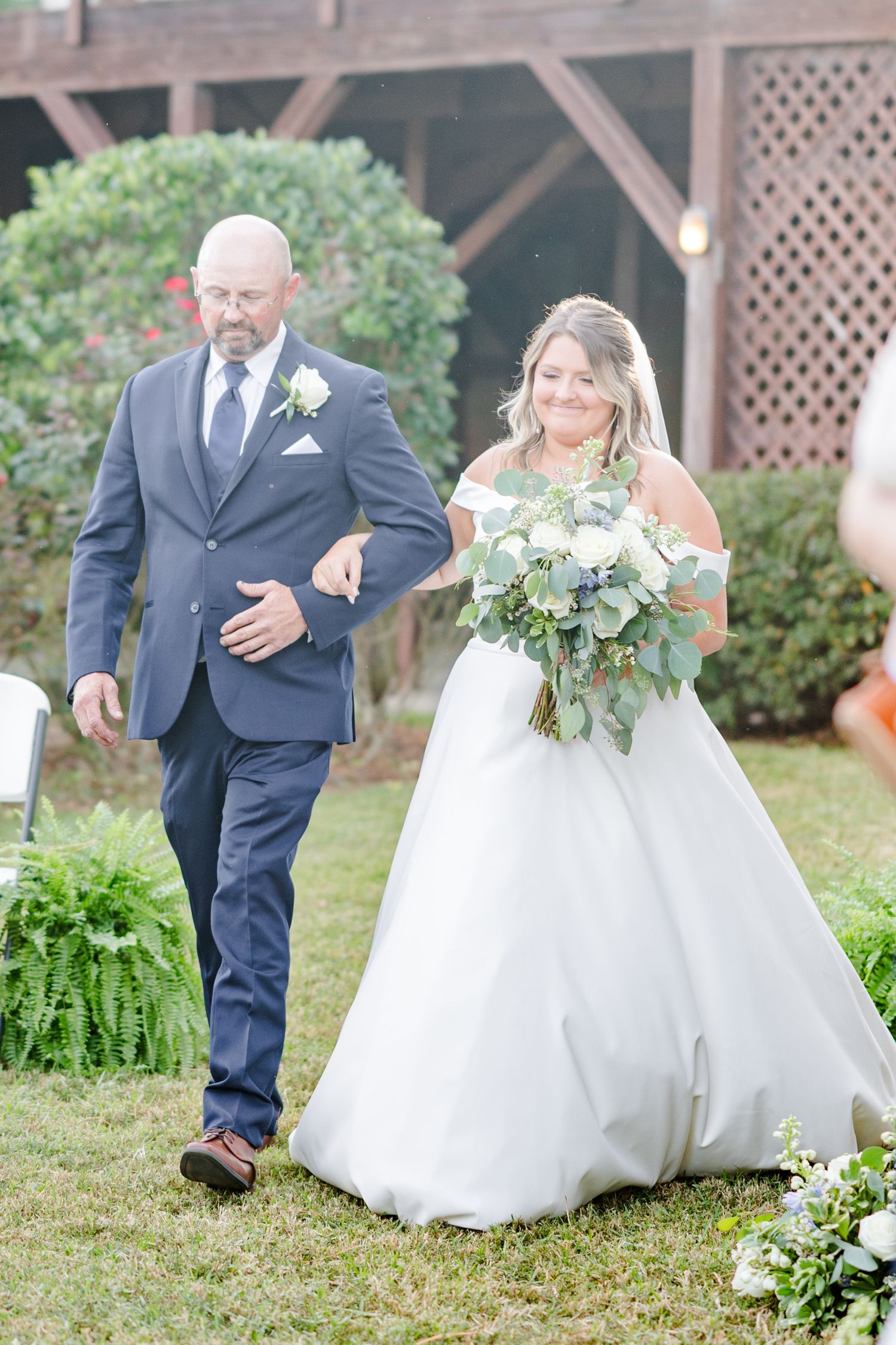 Wedding couple walks through garden setting during outdoor photo session.