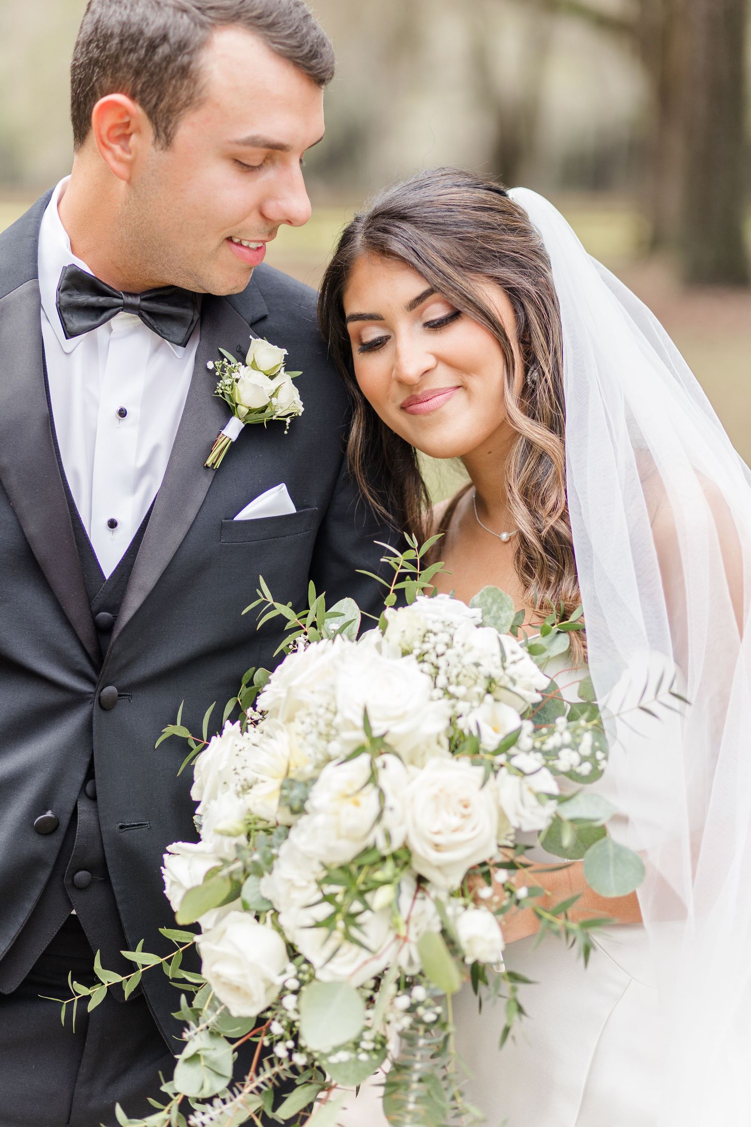 Romantic wedding portraits featuring white roses and eucalyptus bouquet with flowing veil.