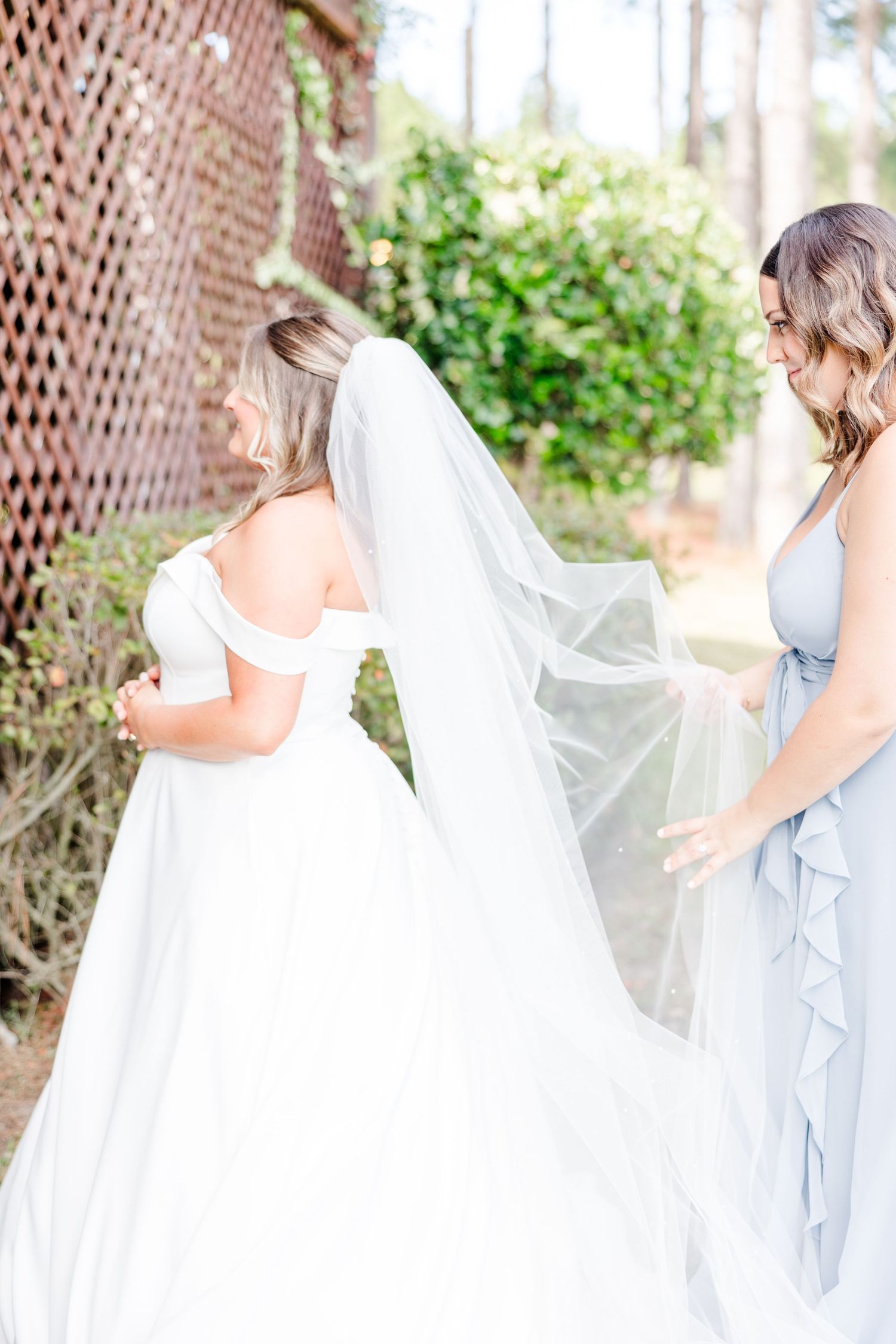 Flowing white wedding gown movement captured against rustic lattice background.