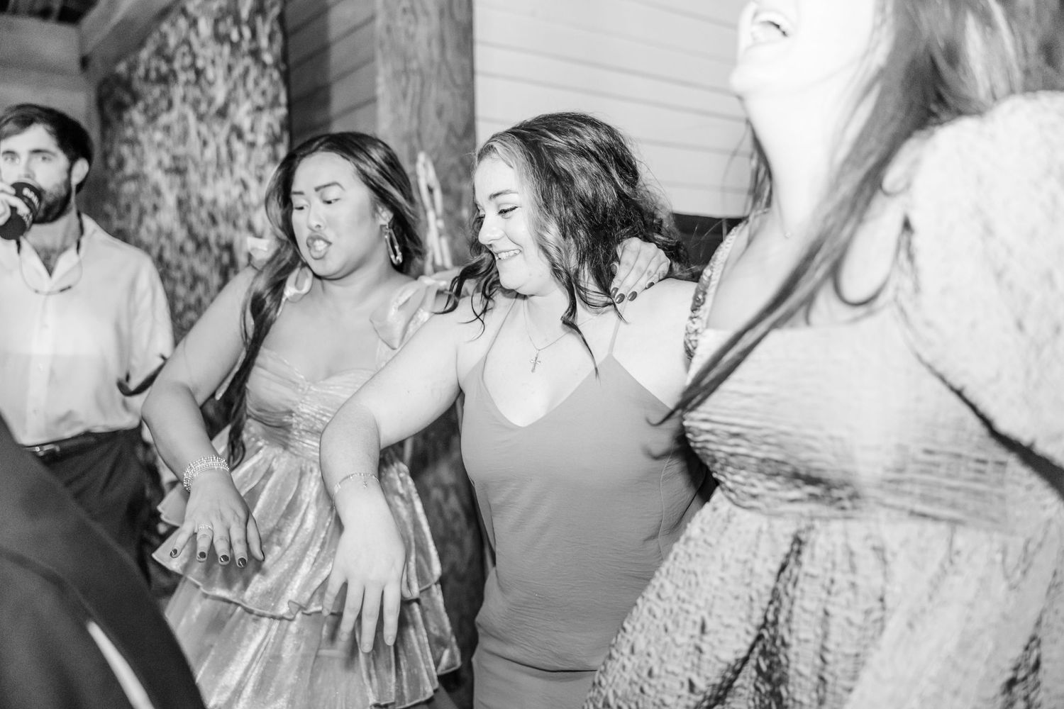 Black and white shot of wedding guests dancing energetically at reception.