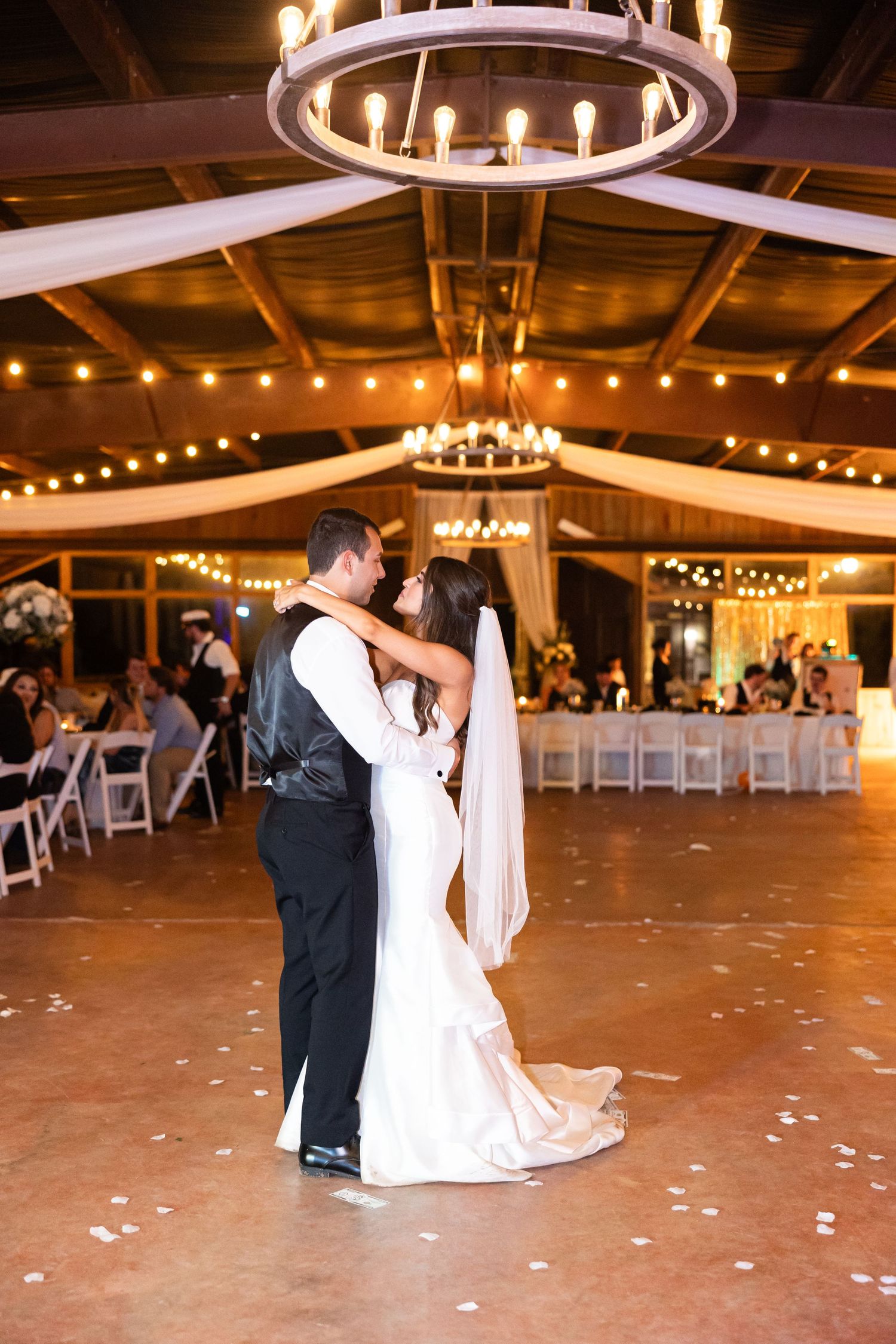 Romantic dance moment under a grand chandelier in a rustic wooden venue.