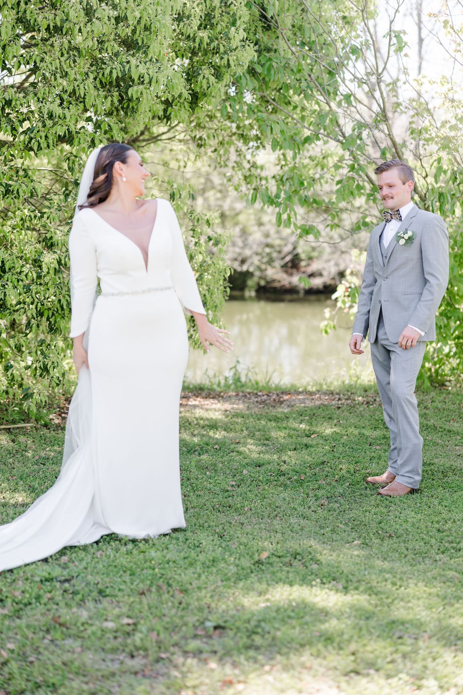 Scenic outdoor wedding photos taken by a pond with lush greenery.