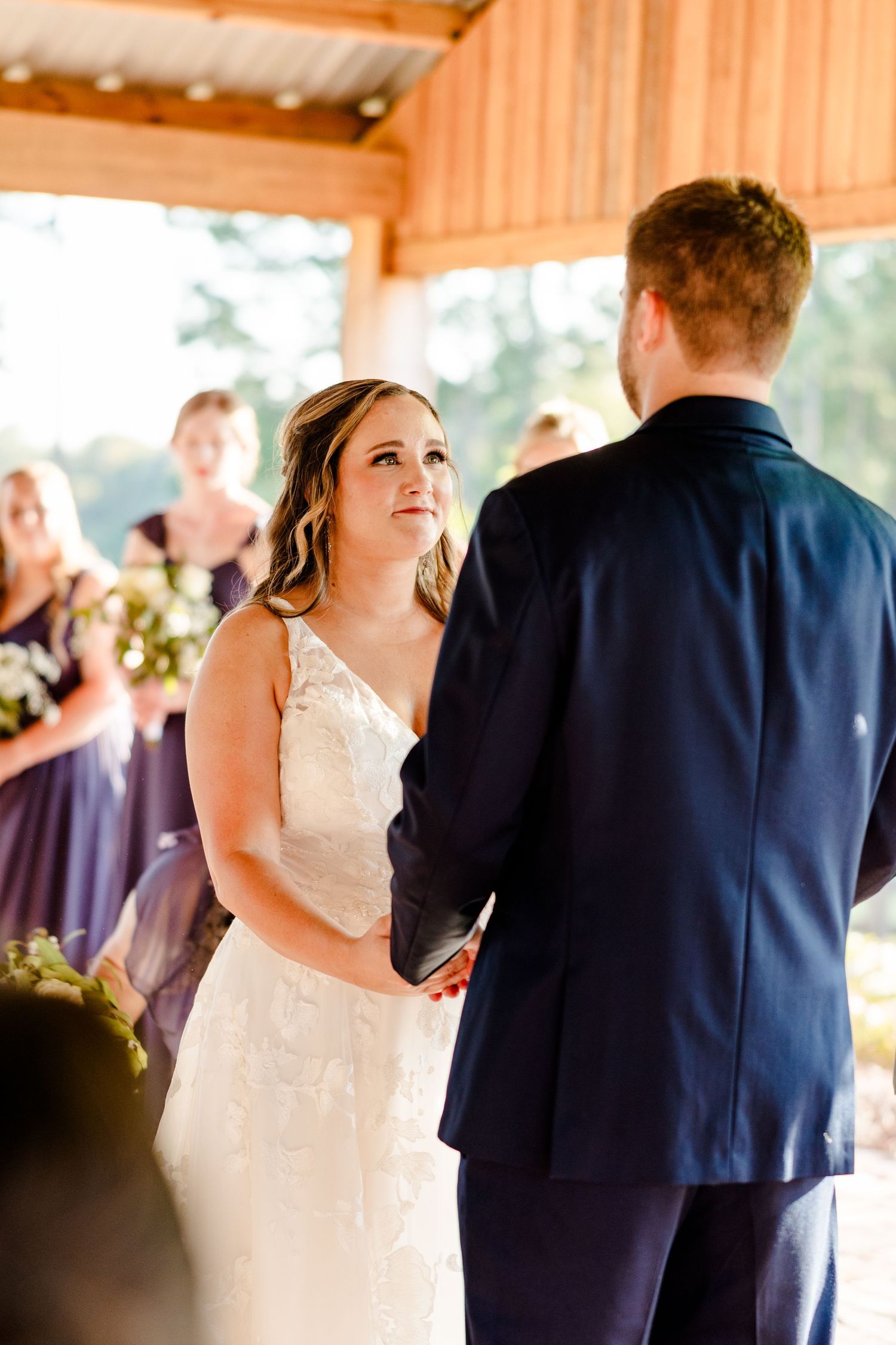 A couple shares a romantic moment during their wedding ceremony in a wooden barn.
