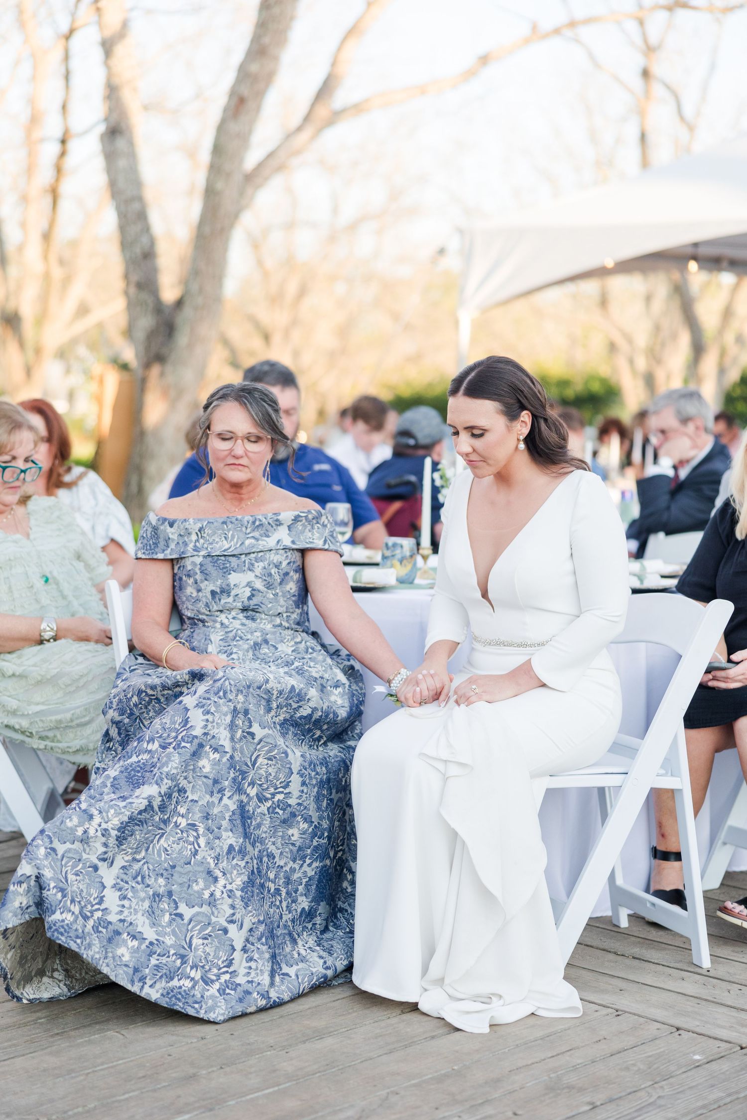 Wedding guests relaxing in white chairs at outdoor reception.