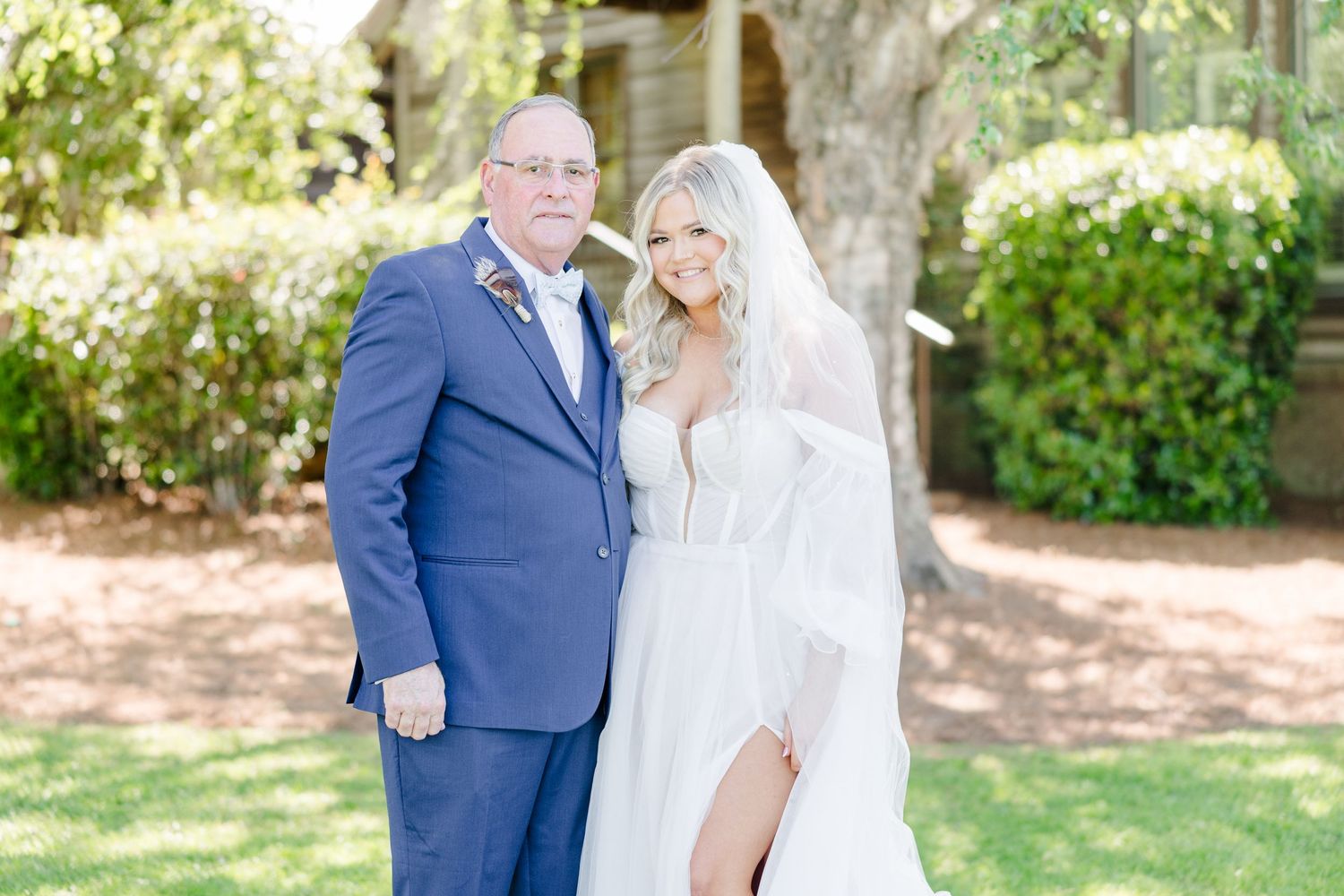 Newlywed couple poses in garden setting with bride in white and groom in navy suit.