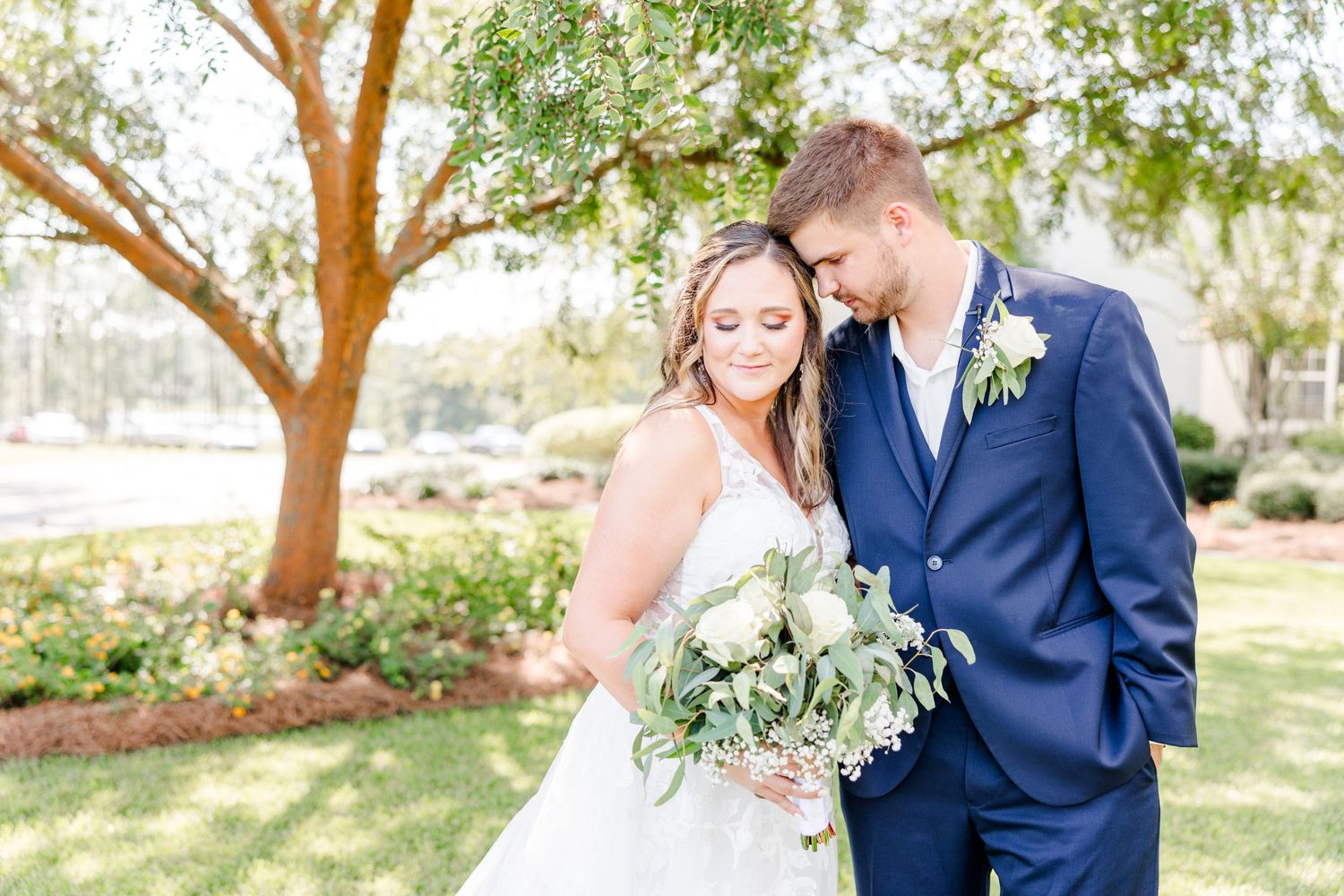 Elegant wedding portraits showcase couple in navy and white against natural outdoor backdrop.