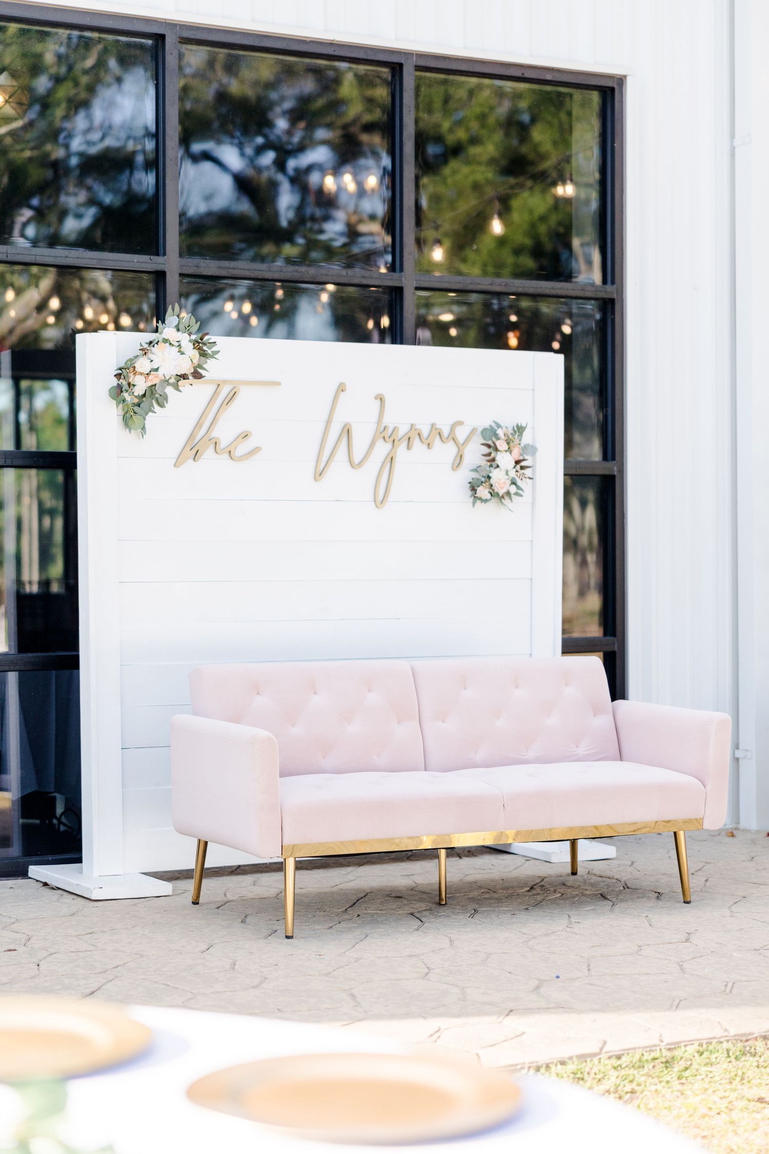 Modern white wedding venue exterior with elegant pink lounge seating and gold accents.