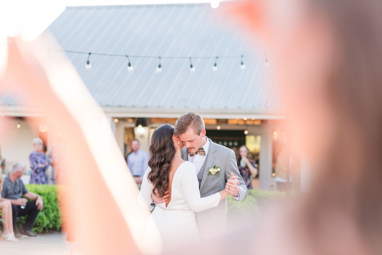 White tent with string lights set up for outdoor wedding reception.