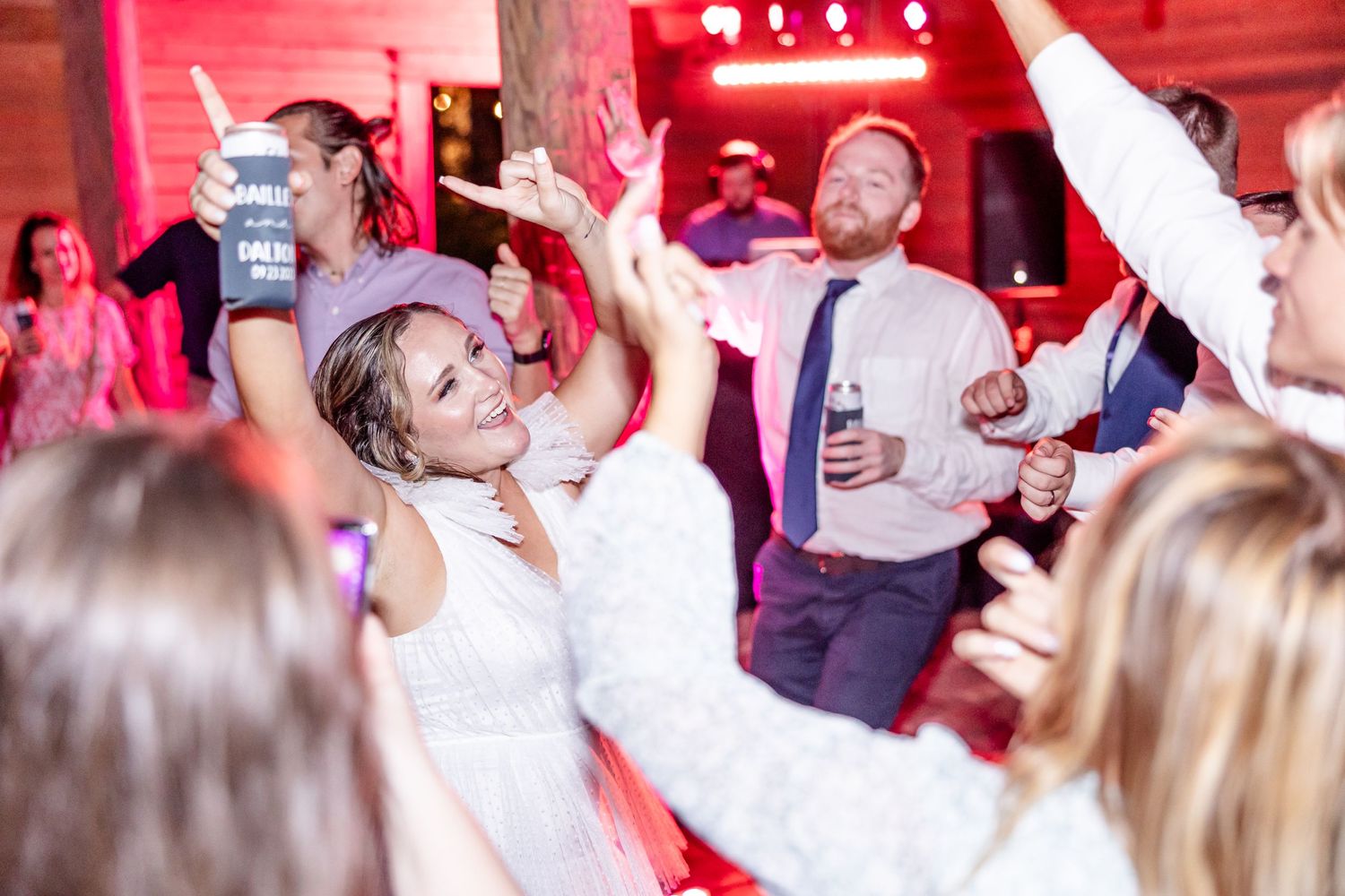 Wedding reception dance floor illuminated with red lighting as guests celebrate.