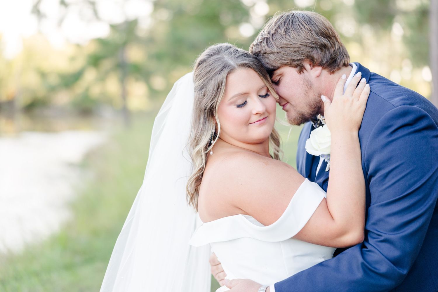 Tender wedding moment photographed under a wooden pavilion with natural lighting.