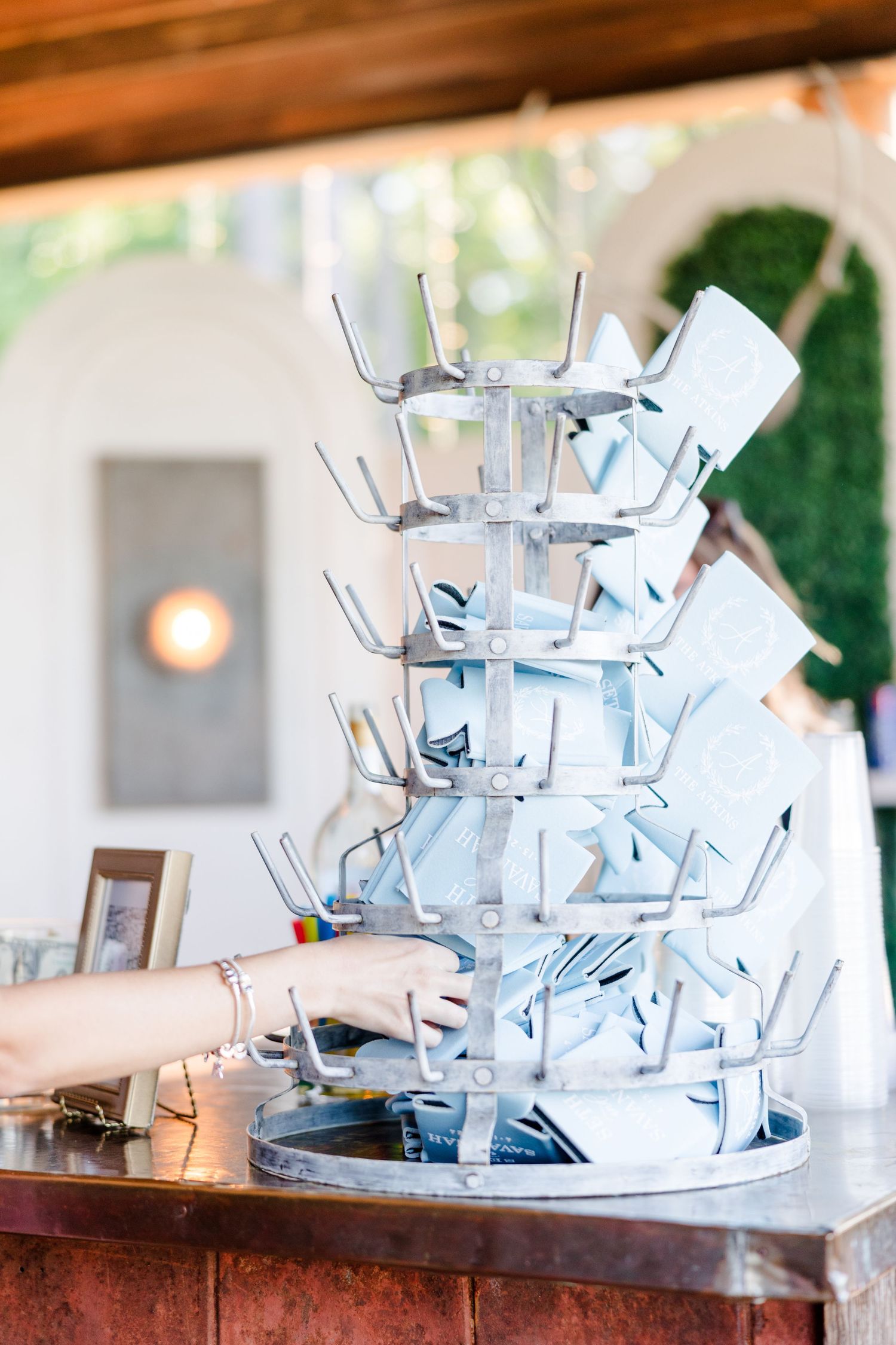 Wedding reception detail of stacked glass drink dispensers on rustic wooden bar.