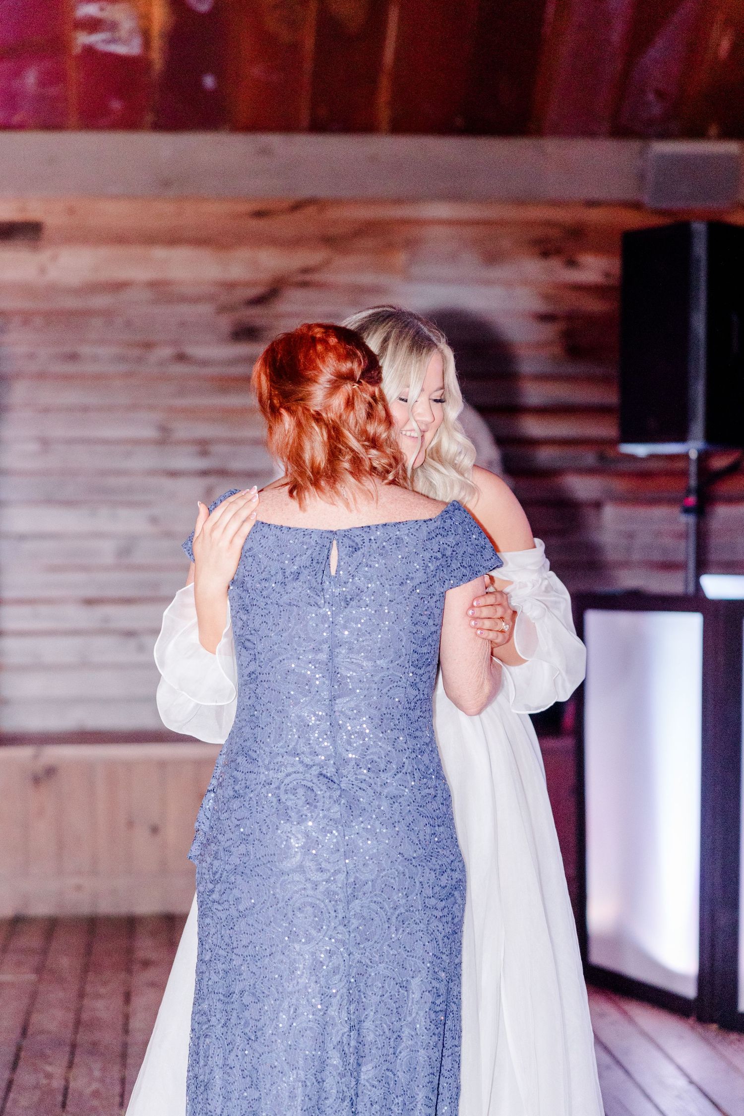 Bridesmaids in pale blue dresses sharing emotional embraces during wedding celebration.